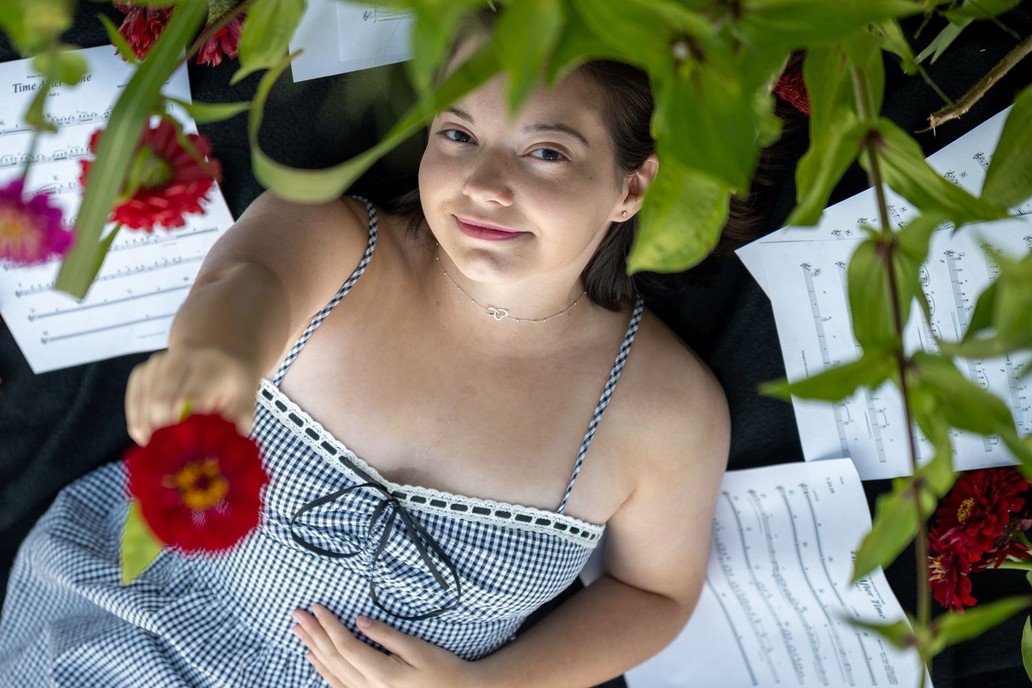 Artistic portrait with red flowers and greenery framing the composition.