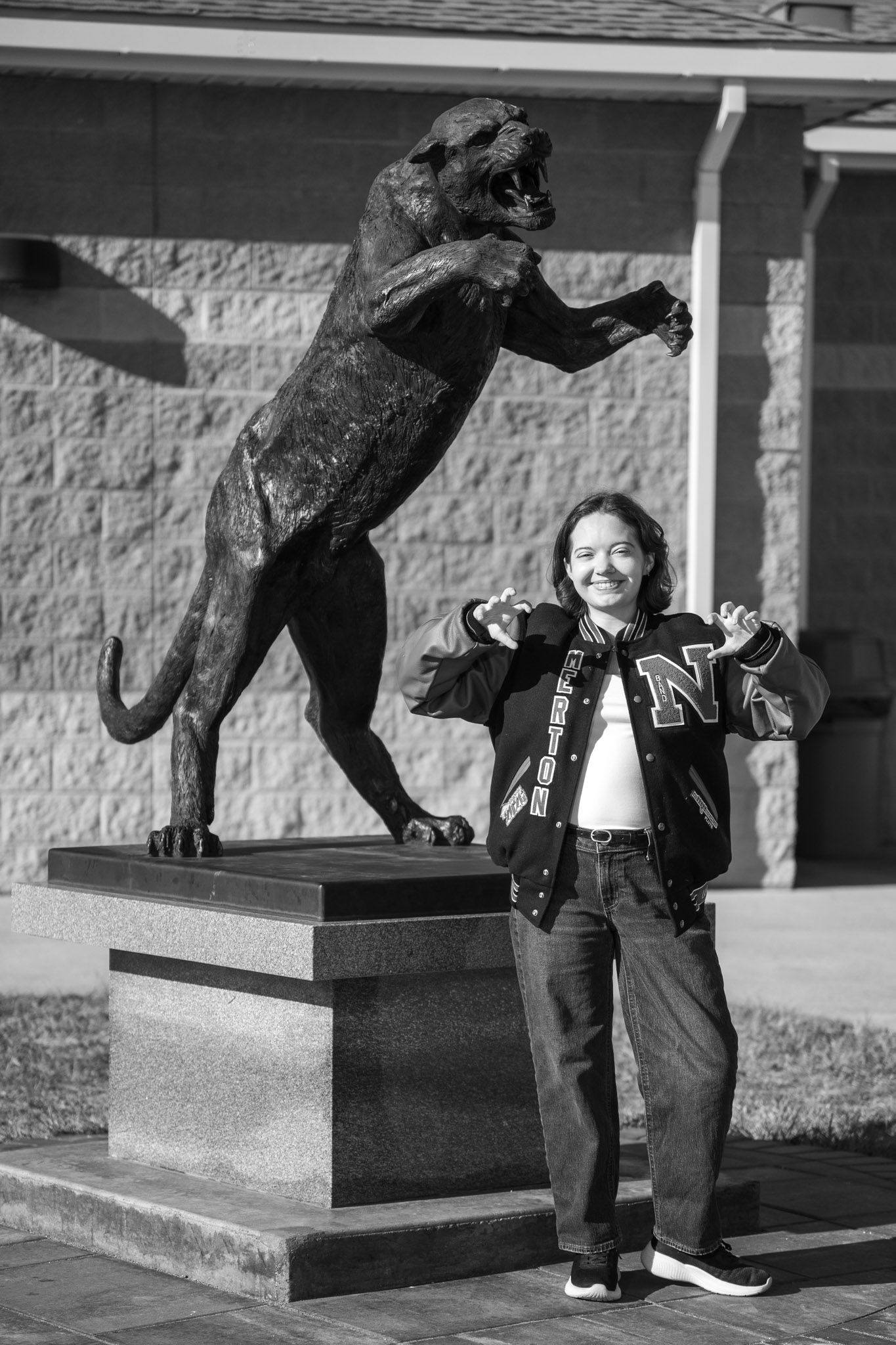 Playful pose with a large bronze wildcat statue on a stone pedestal.