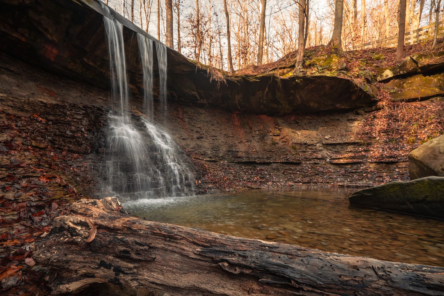 Scenic waterfall cascading over rocky ledges in a forest setting during autumn.