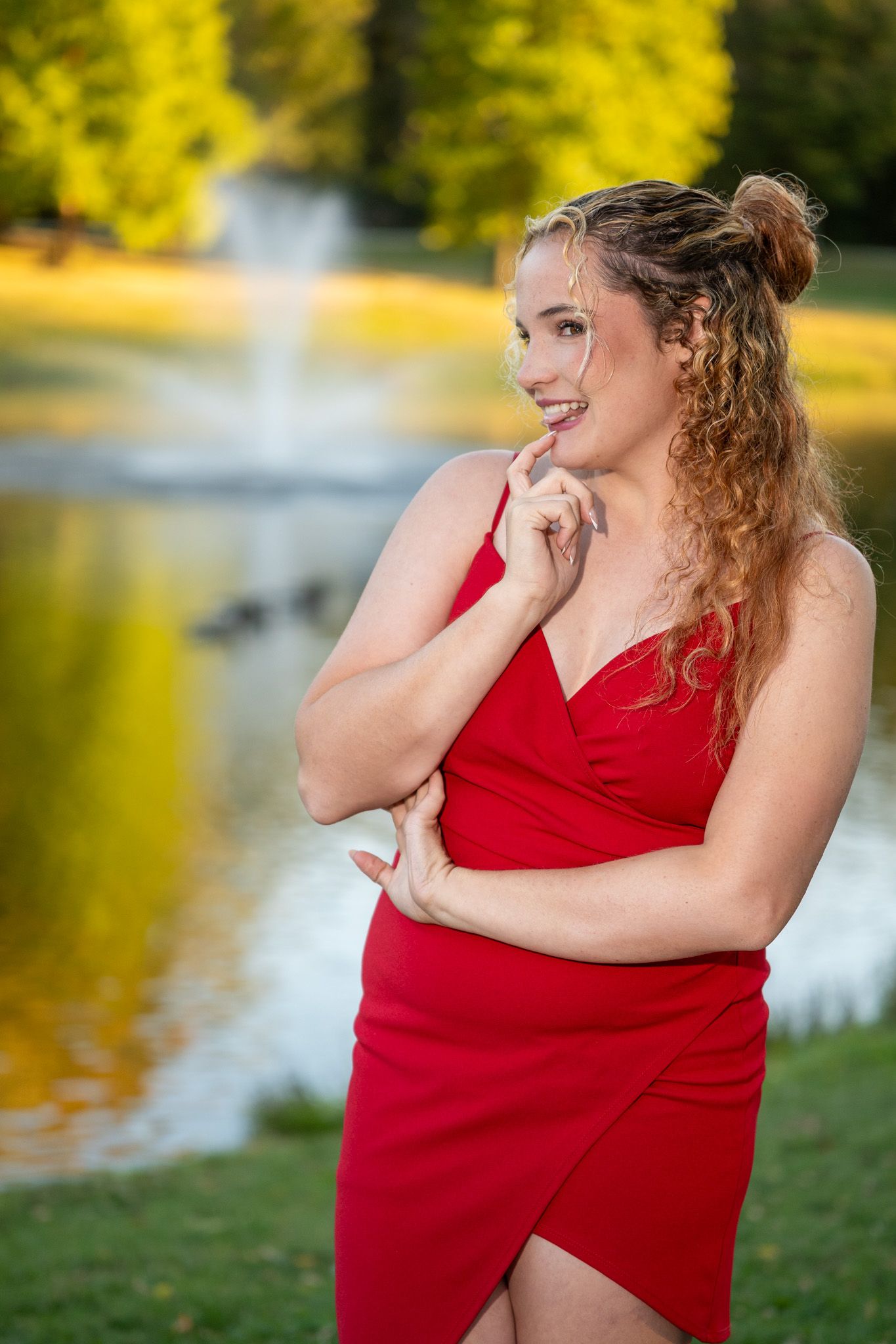 Elegant lakeside portrait series showing contemplative poses in a flowing red dress.
