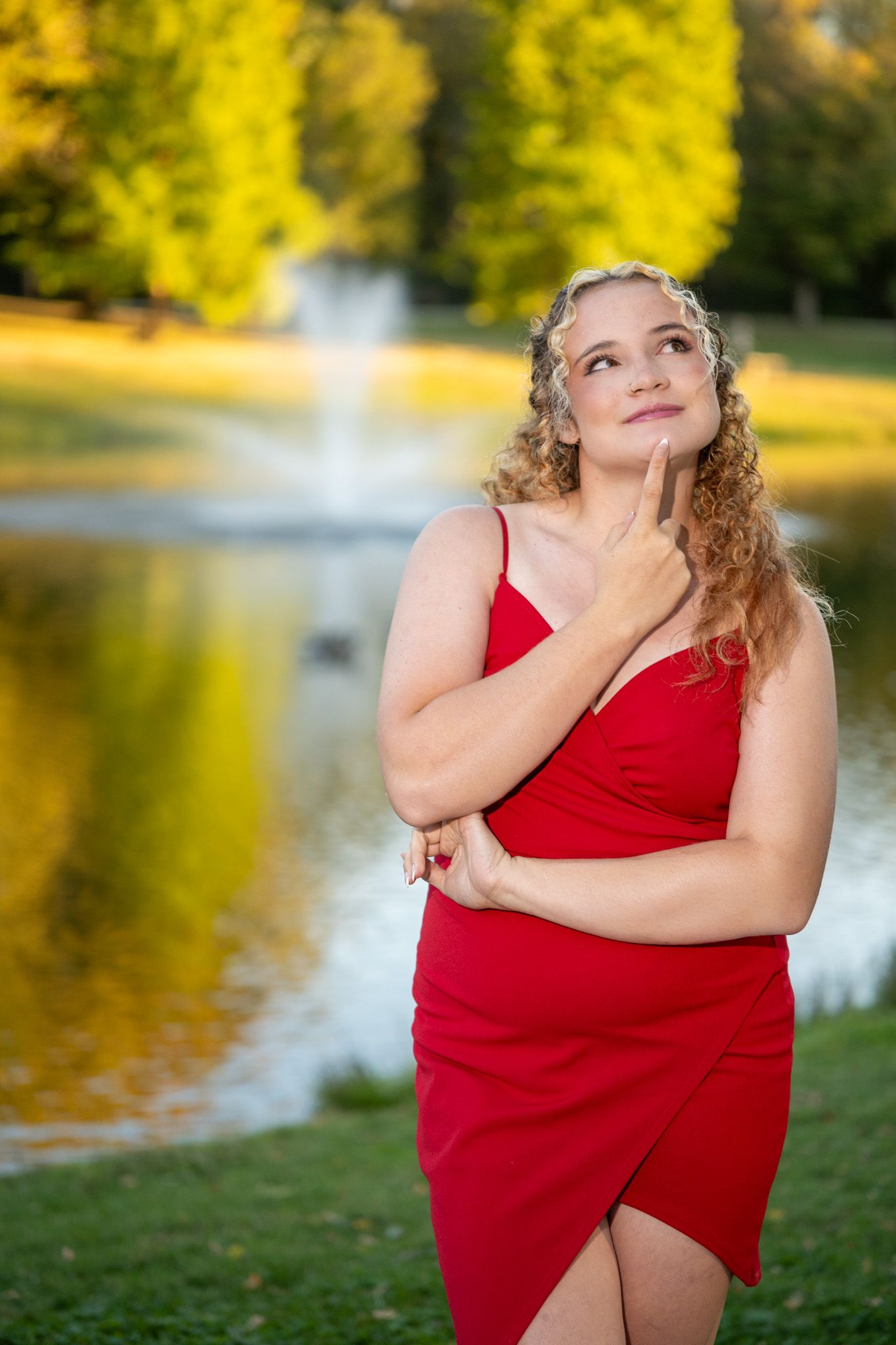 Artistic outdoor portraits by a lake featuring someone in a red dress with golden sunset lighting.
