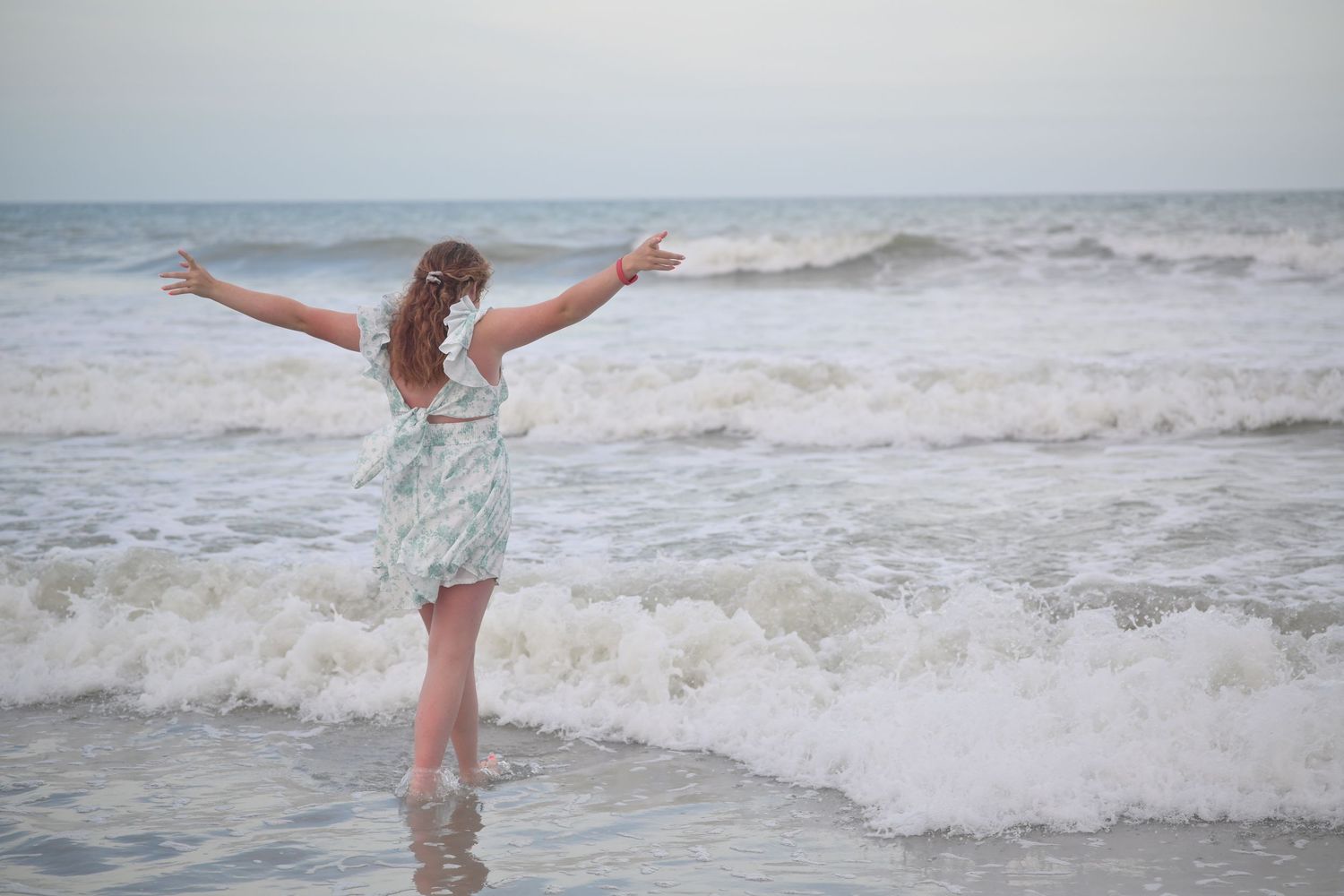 Playful beach portraits showing someone splashing and dancing in the ocean waves.