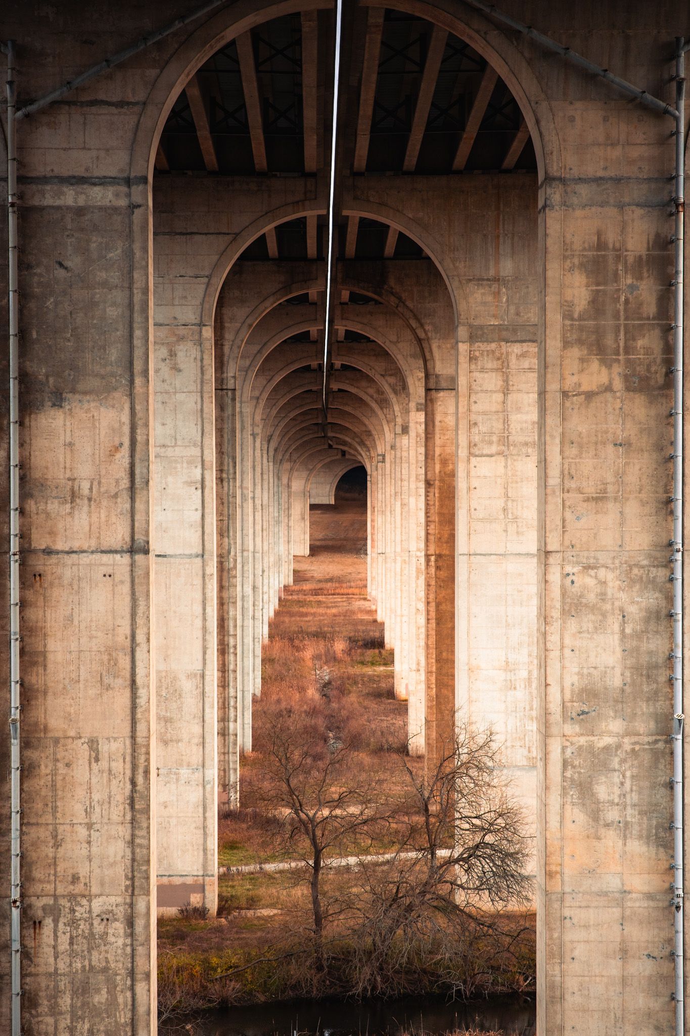 Dramatic arched concrete bridge supports creating symmetrical architectural patterns at sunset.