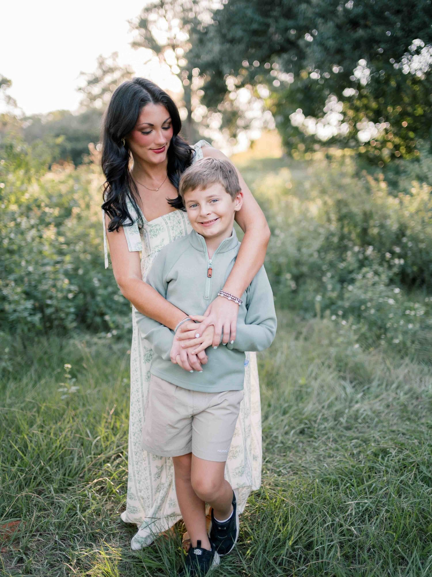 Mom hugging son smiling during a golden hour family photography session at Springhill College