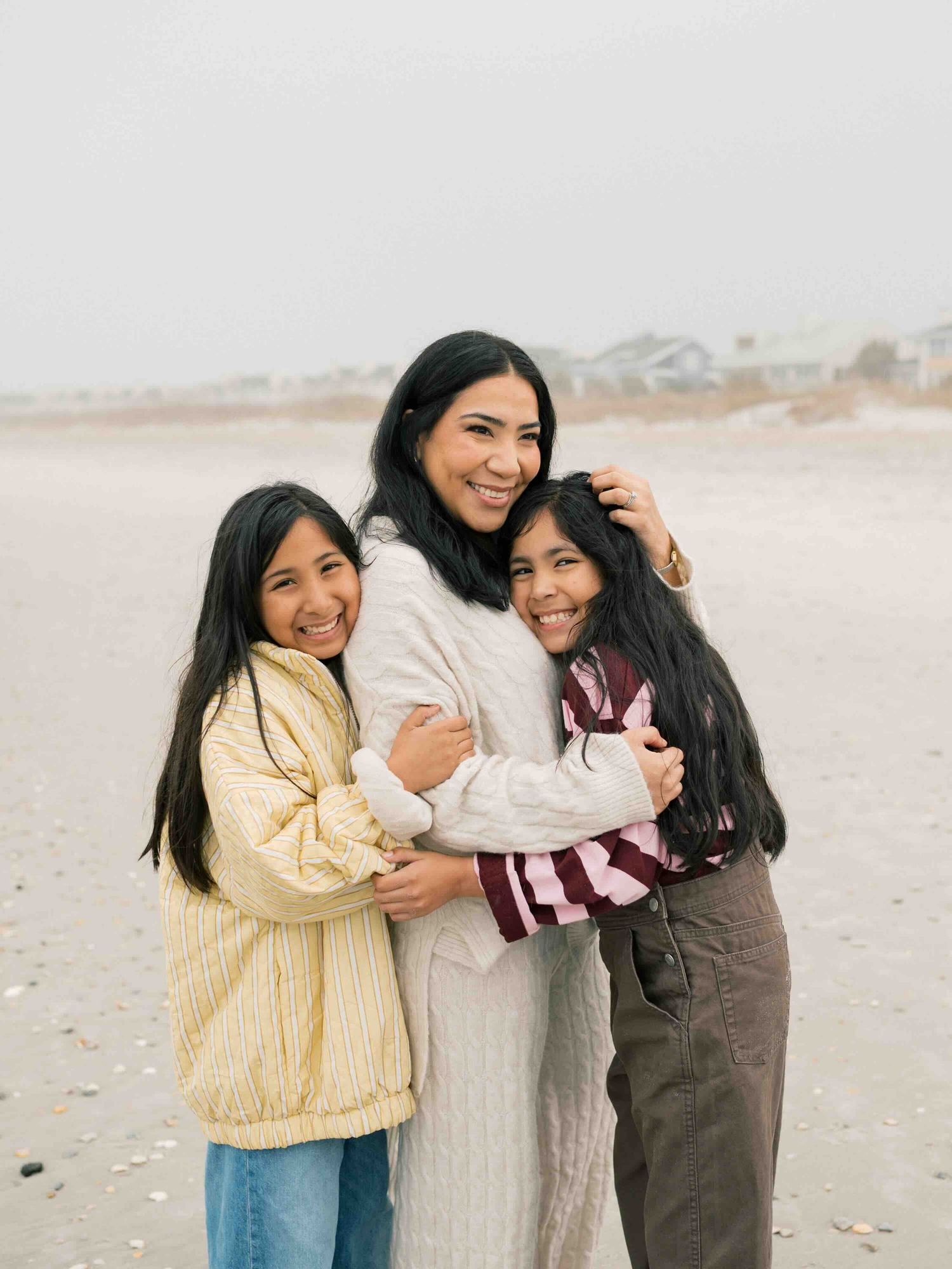Mom embracing daughters during a golden hour beach session on Dauphin Island