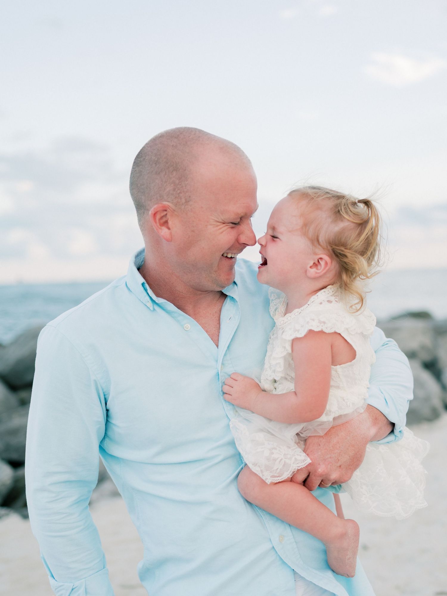 Dad and daughter laughing and snuggling close during golden hour session in Dauphin Island, Alabama