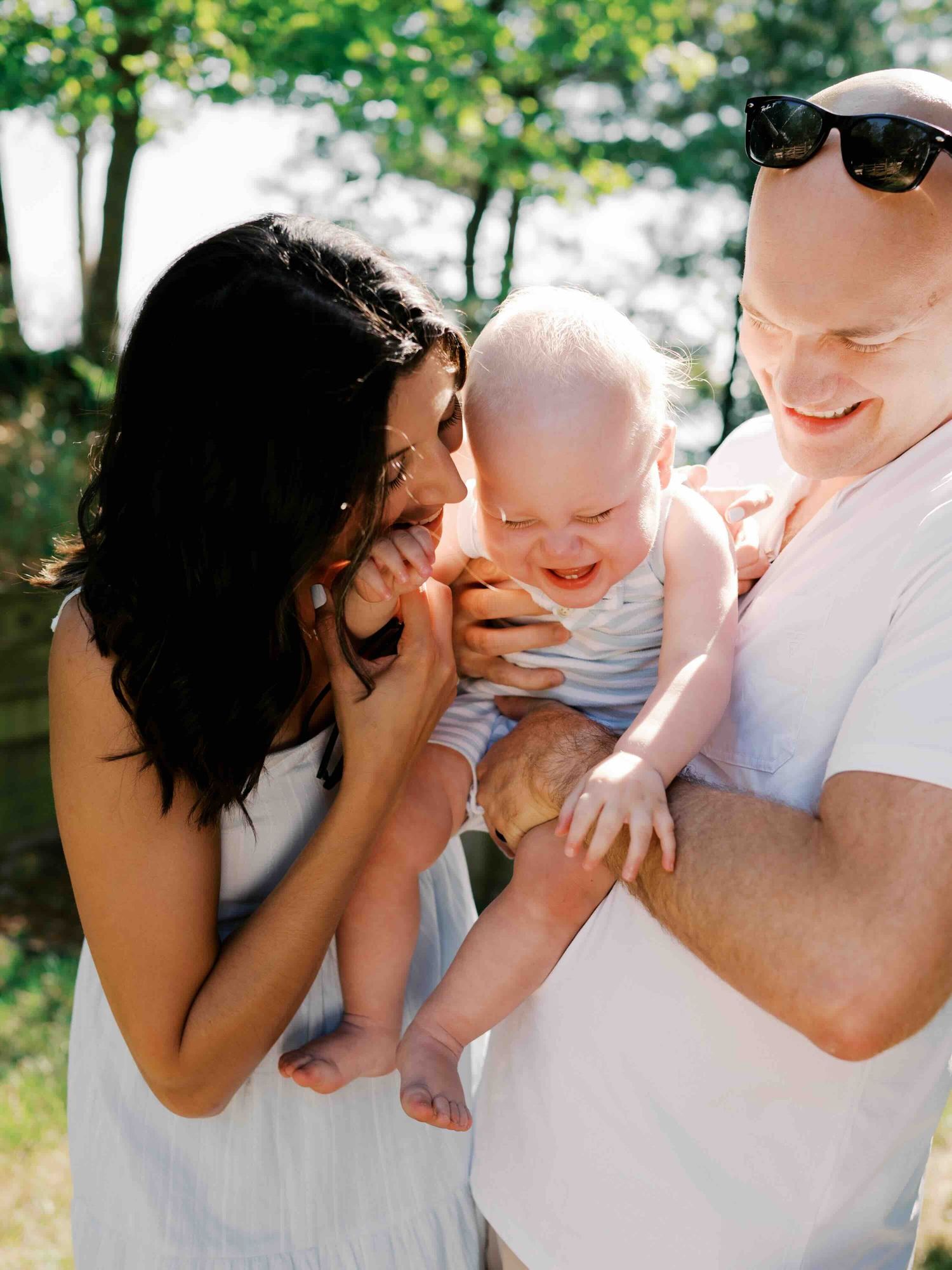 Mom and dad tickle baby brother during their outdoor family photos in Mobile, Alabama.