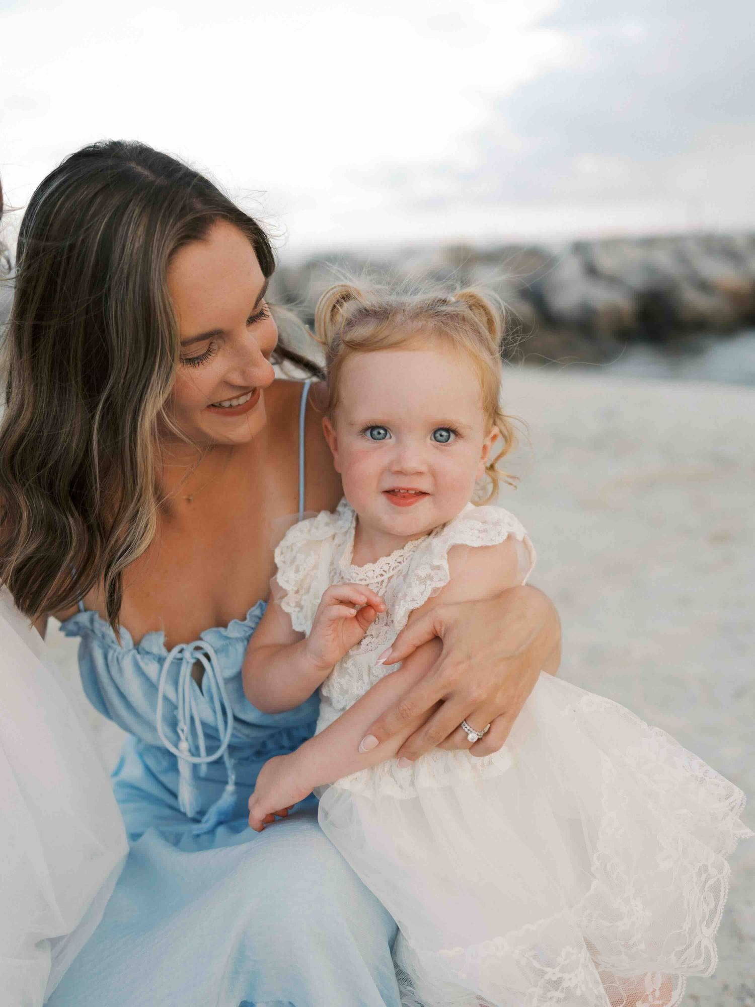 mom snuggling daughter along the beach at Dauphin Island during a family photo session.