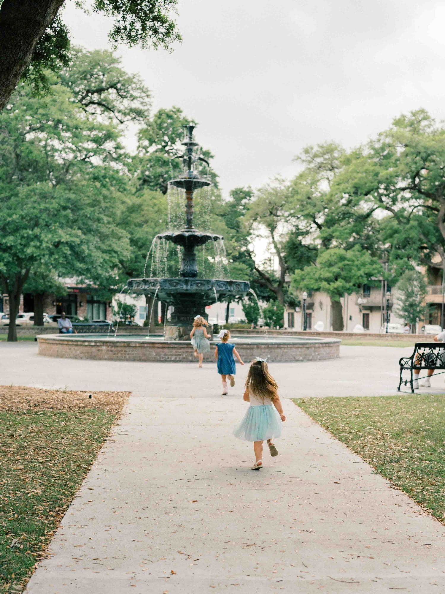 three little girls running towards fountain in Bienville Square during a photo shoot in Mobile Alabama