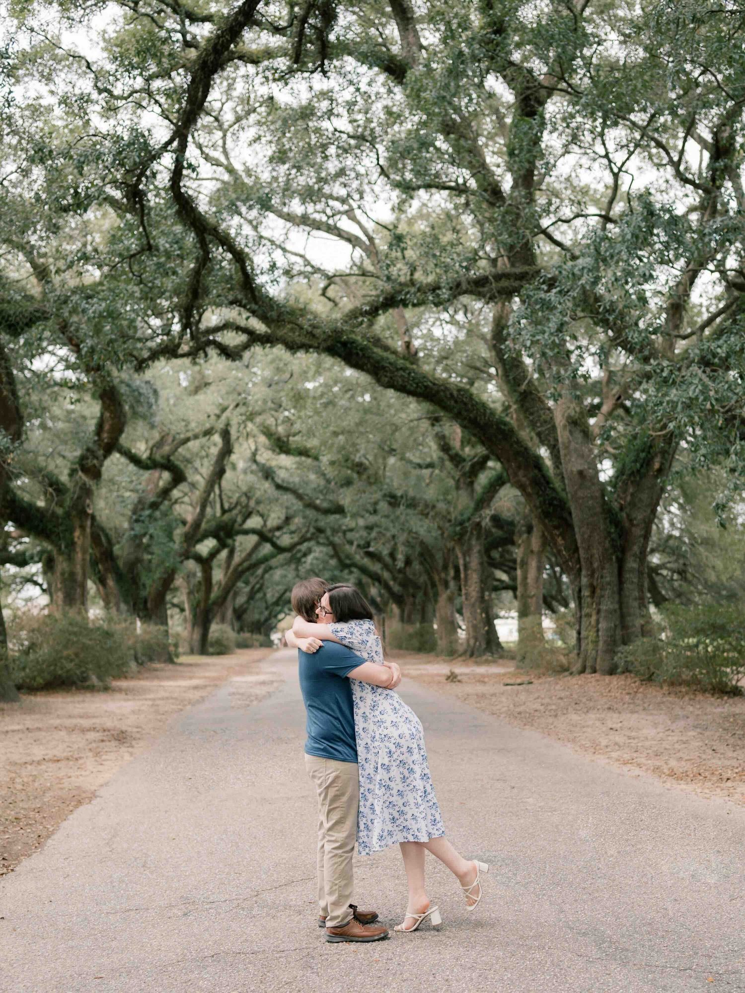 Man and woman embracing under the oaks at Springhill college during an engagement session in Mobile, Alabama