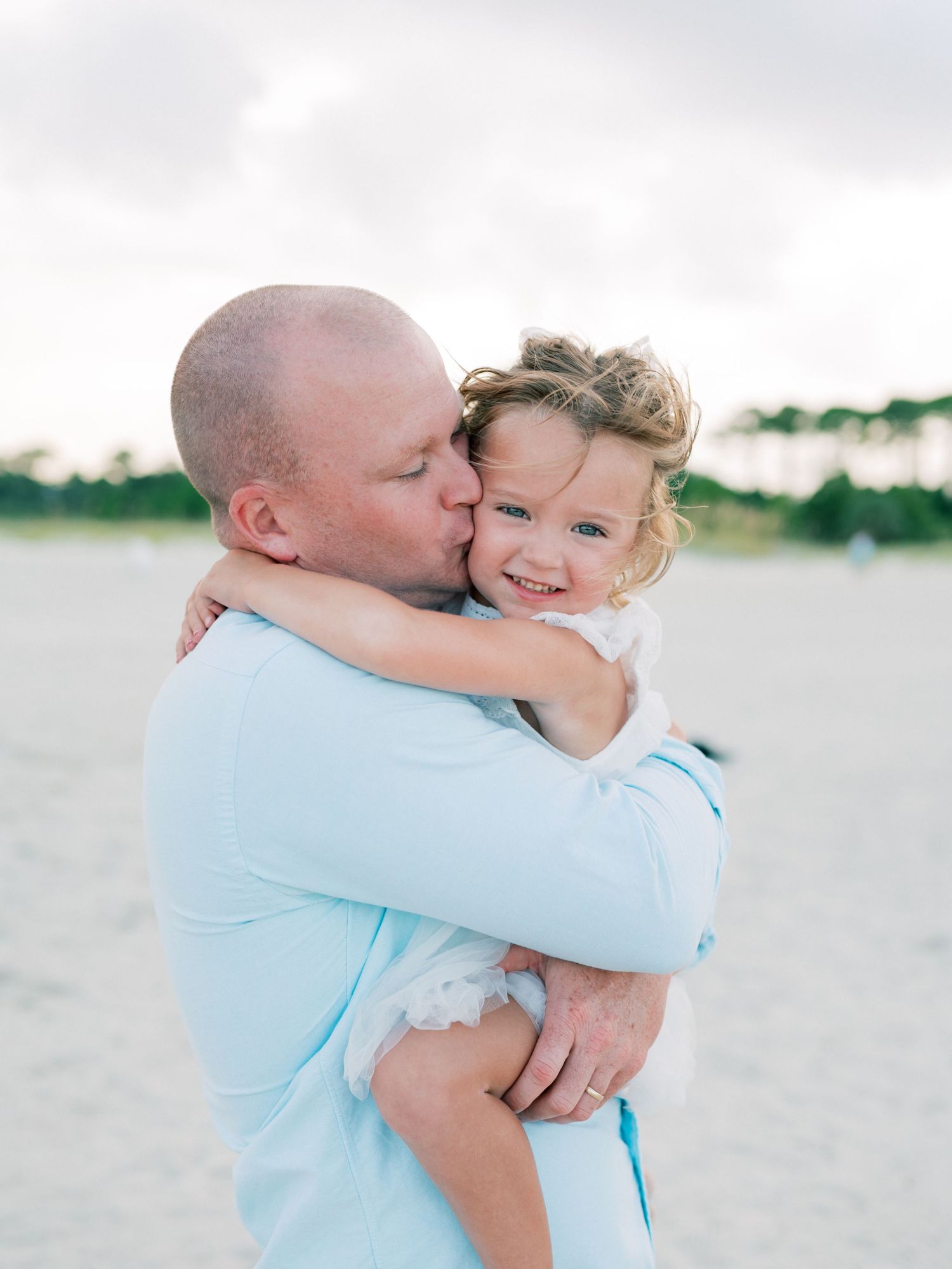Dad and daughter embracing along Dauphin Island beach at sunset