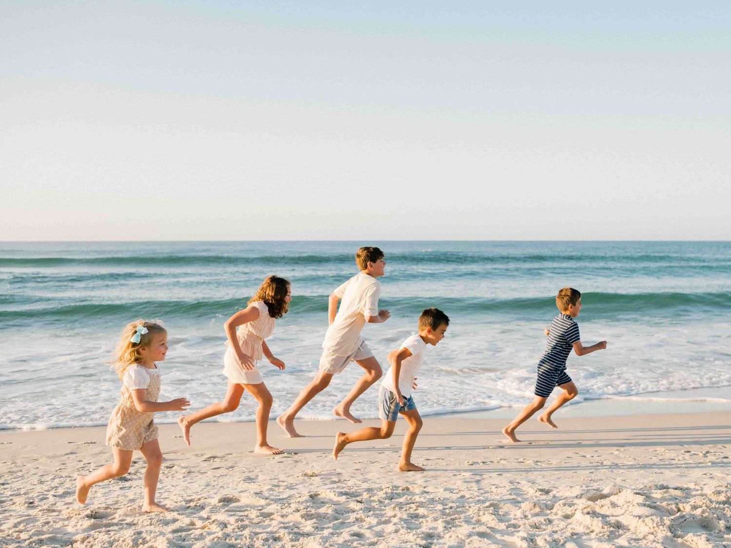 Multi-generational family running along the shoreline during a Dauphin Island beach photo session