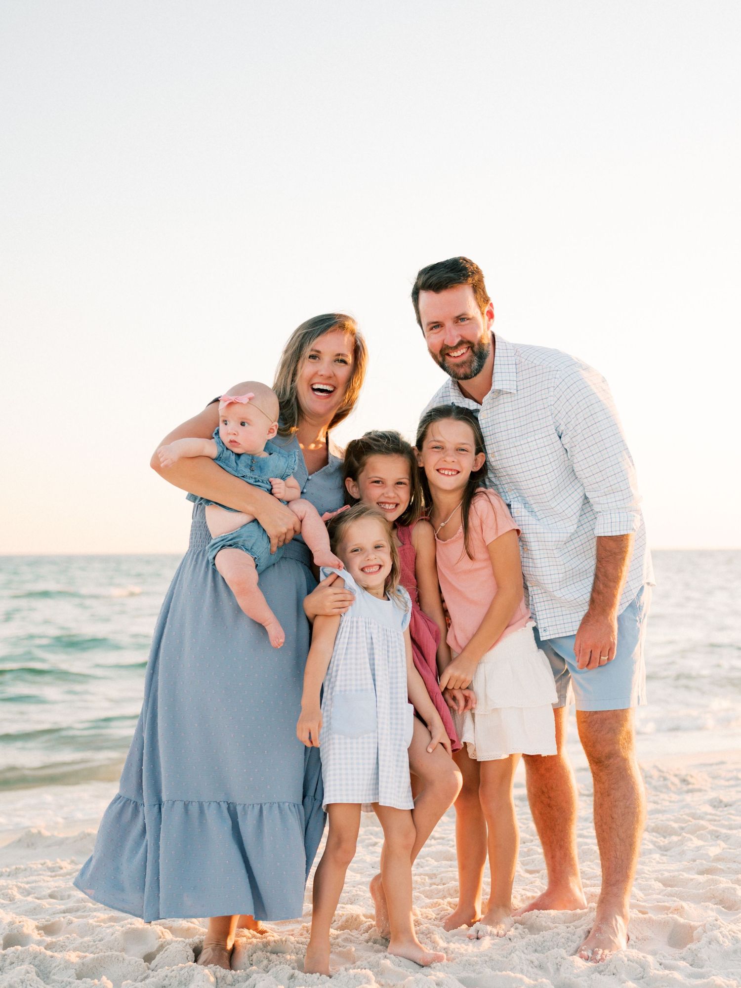 Mother and father laughing with daughters during natural light family photography session in Fairhope Alabama
