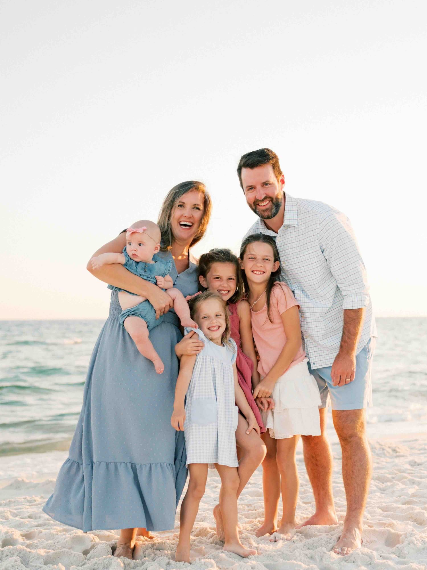 Family hugging along shoreline during relaxed beach photography session in Orange Beach