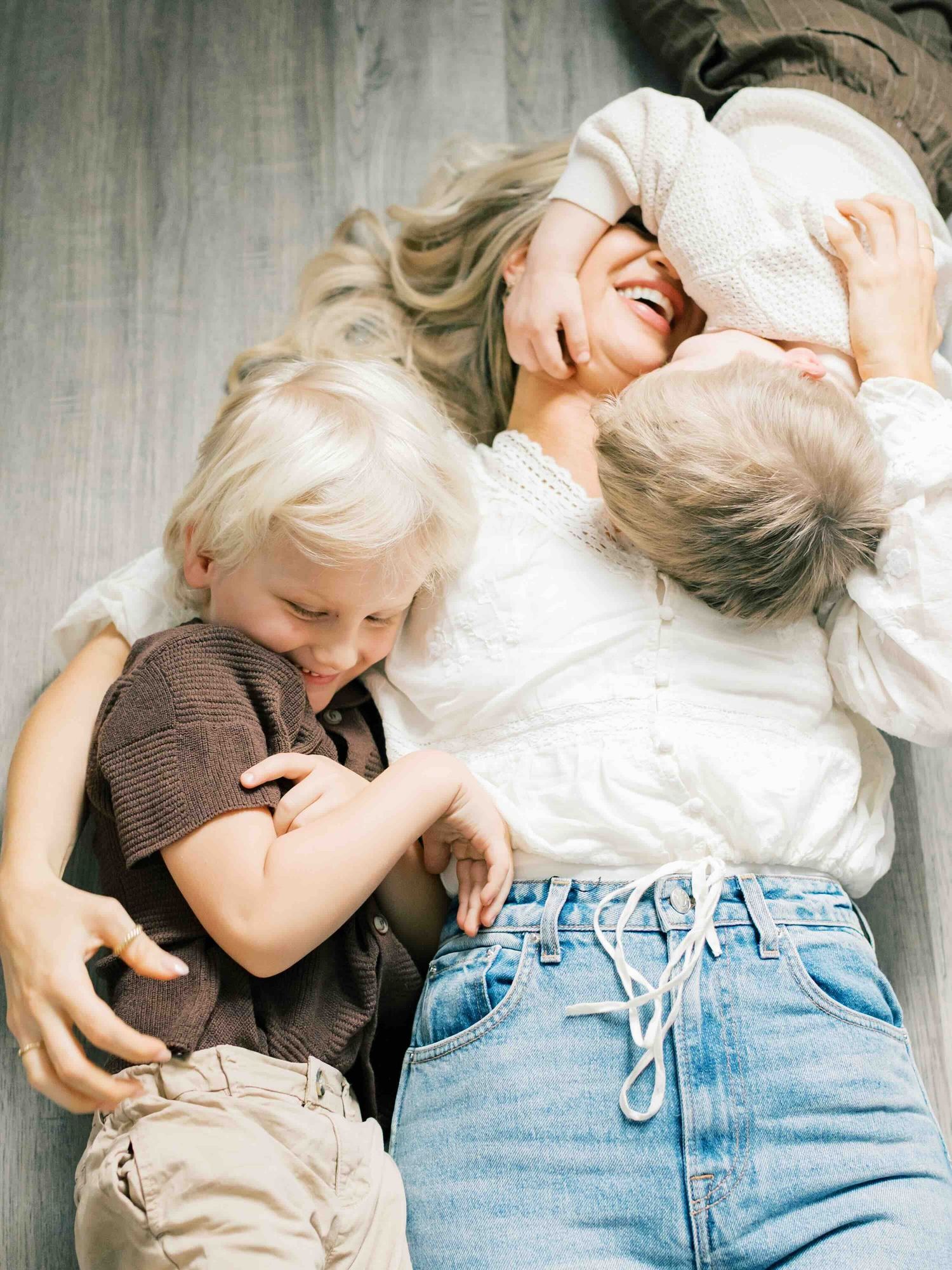 Siblings hugging mom during natural light family photography session in Fairhope Alabama