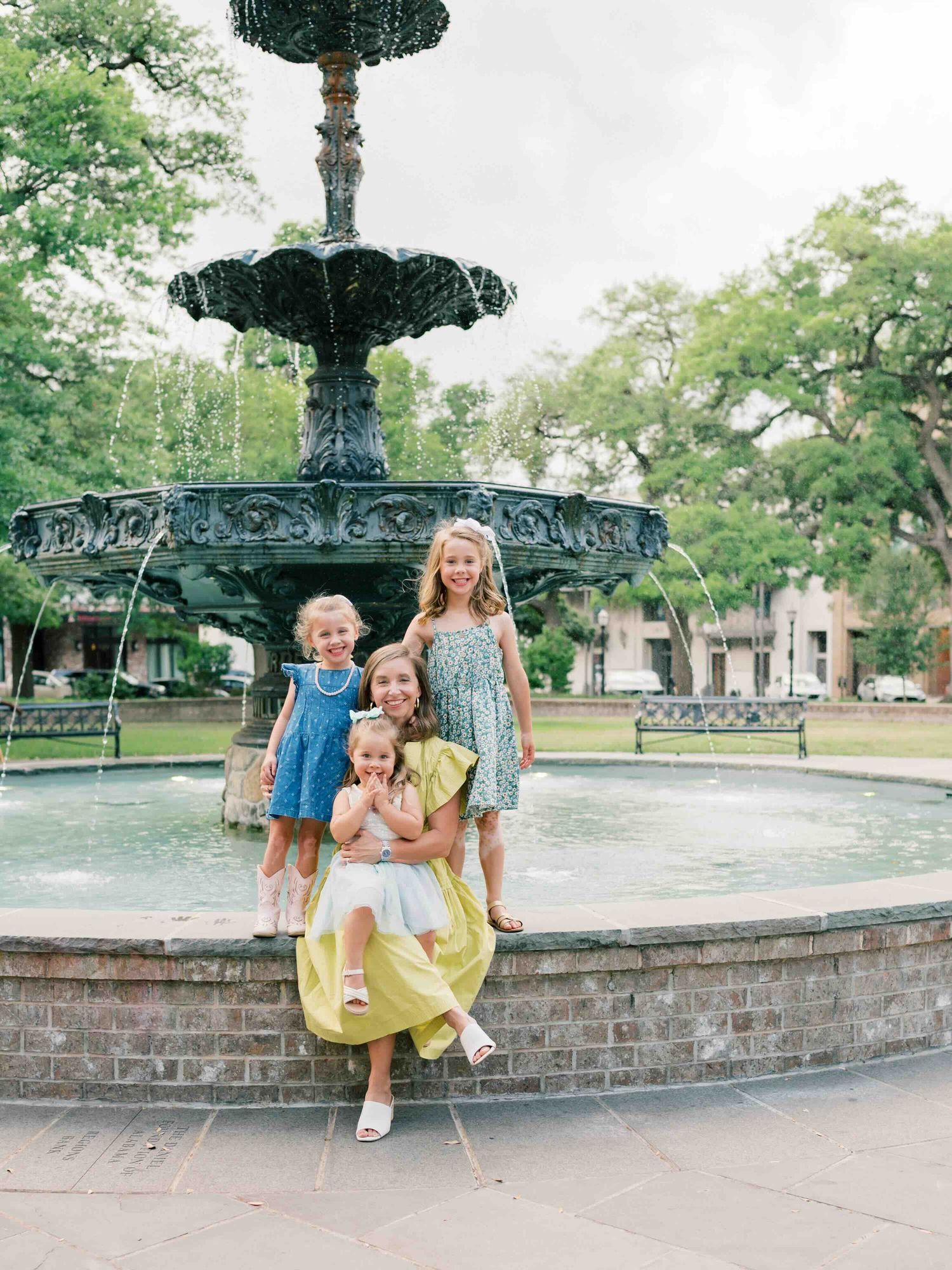 Family photographer capturing candid moment between mom and daughters in Bienville Square Mobile Alabama