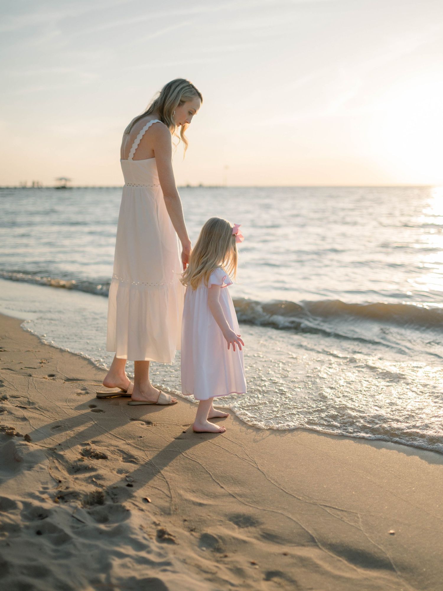 Mom and daughter walking along the shoreline during Fairhope sunset beach photo session.
