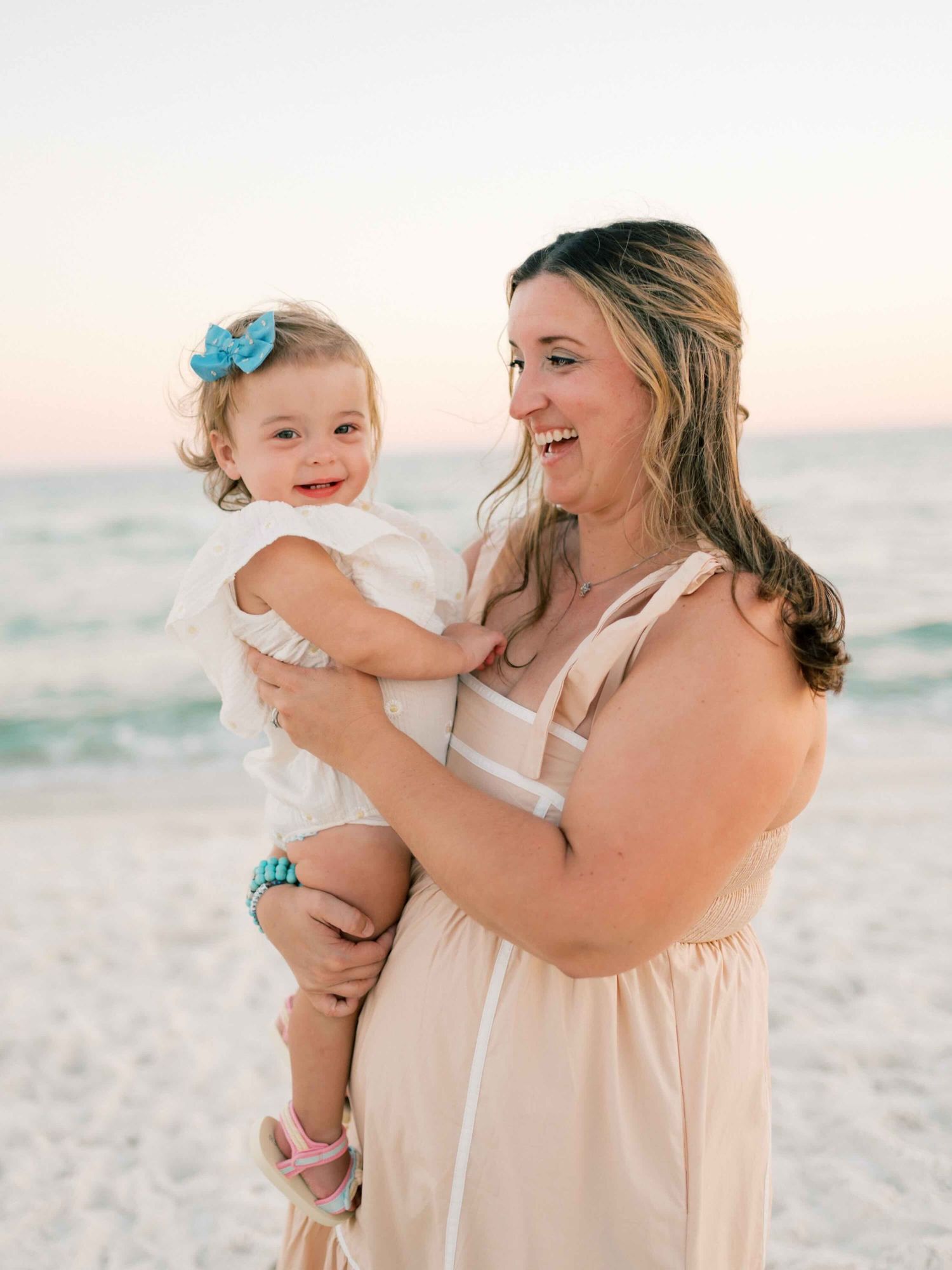 mom embracing daughter and smiling during sunset photo session in Orange Beach Alabama