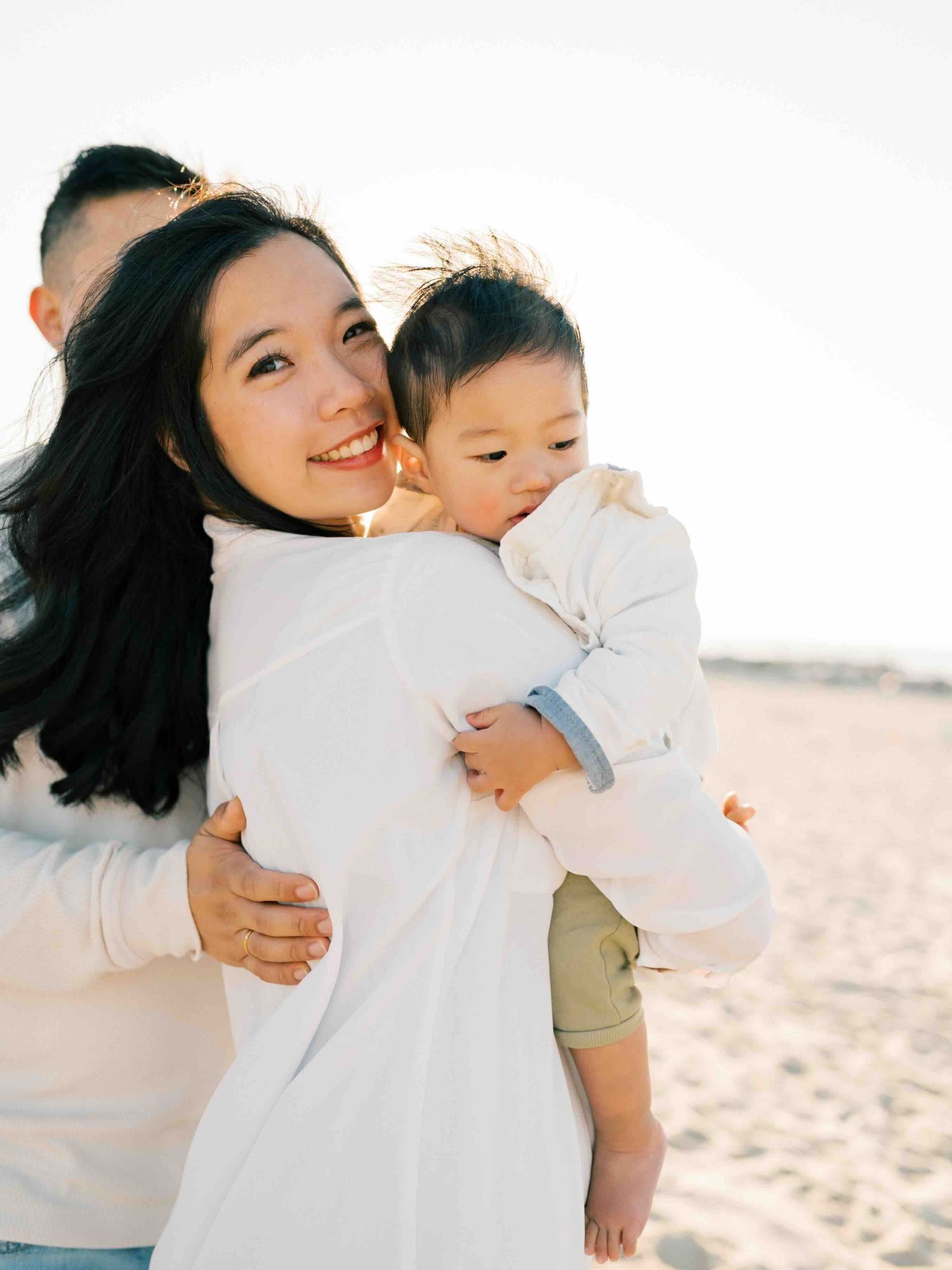 Mom holding son and smiling during a sunrise family photography session on Dauphin Island, Alabama. Captured by Mobile family photographer