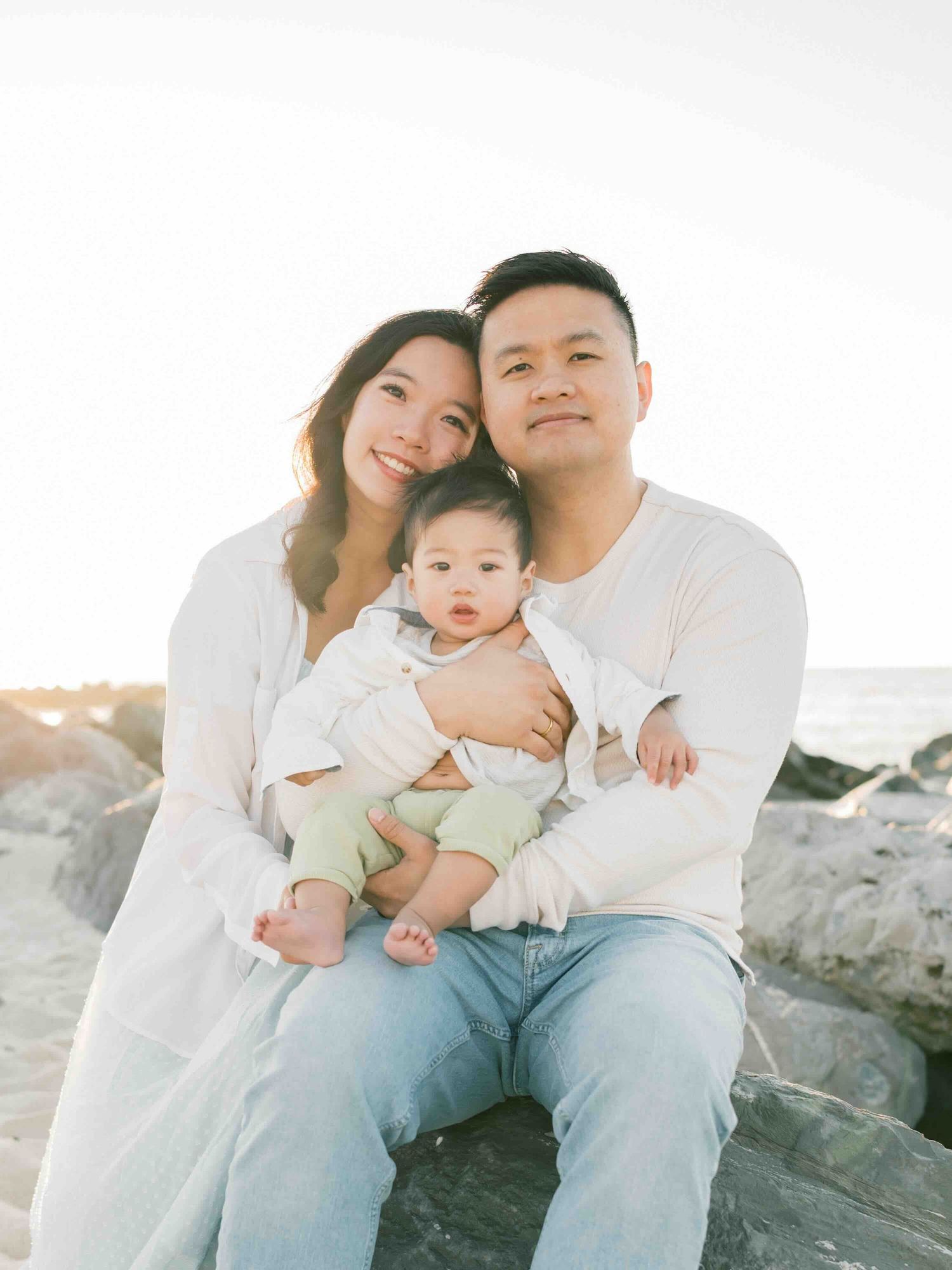 Family photo session at Dauphin Island beach during golden hour with family snuggling up