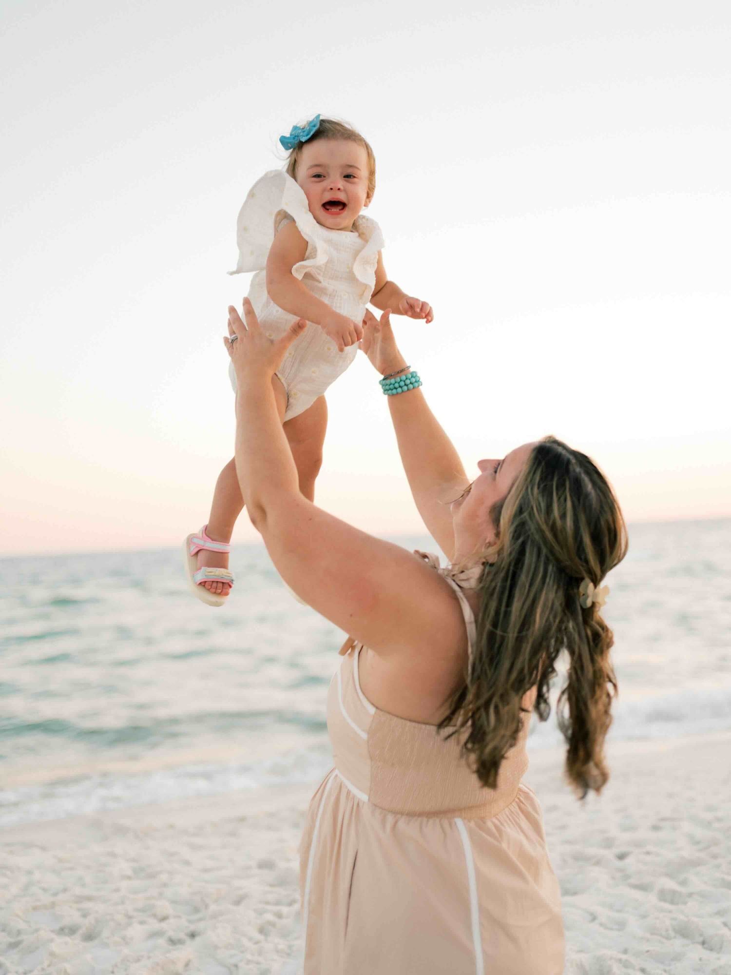 Mom tossing daughter in the air during Orange Beach  family session