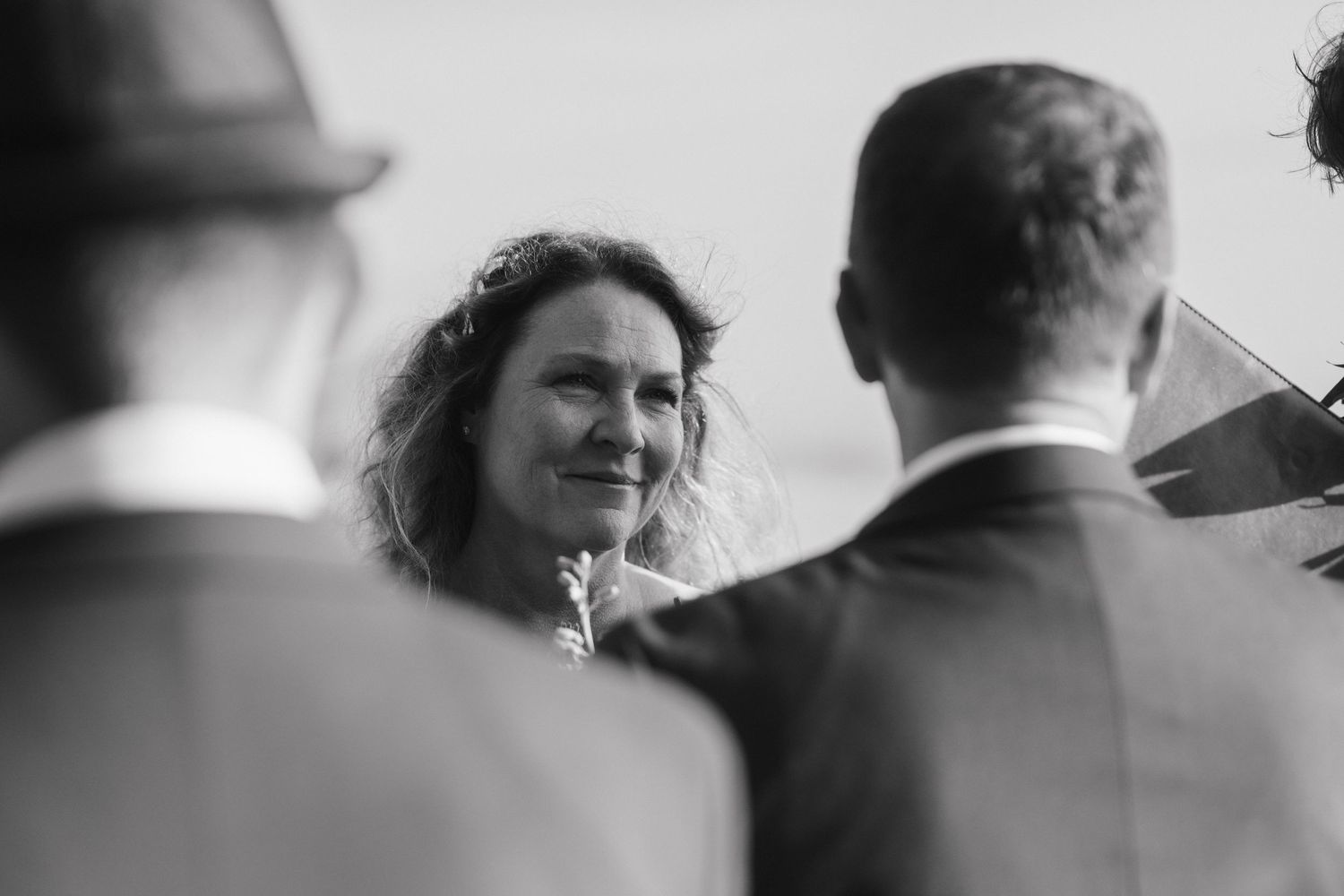 A black and white candid moment during a beachside wedding ceremony.
