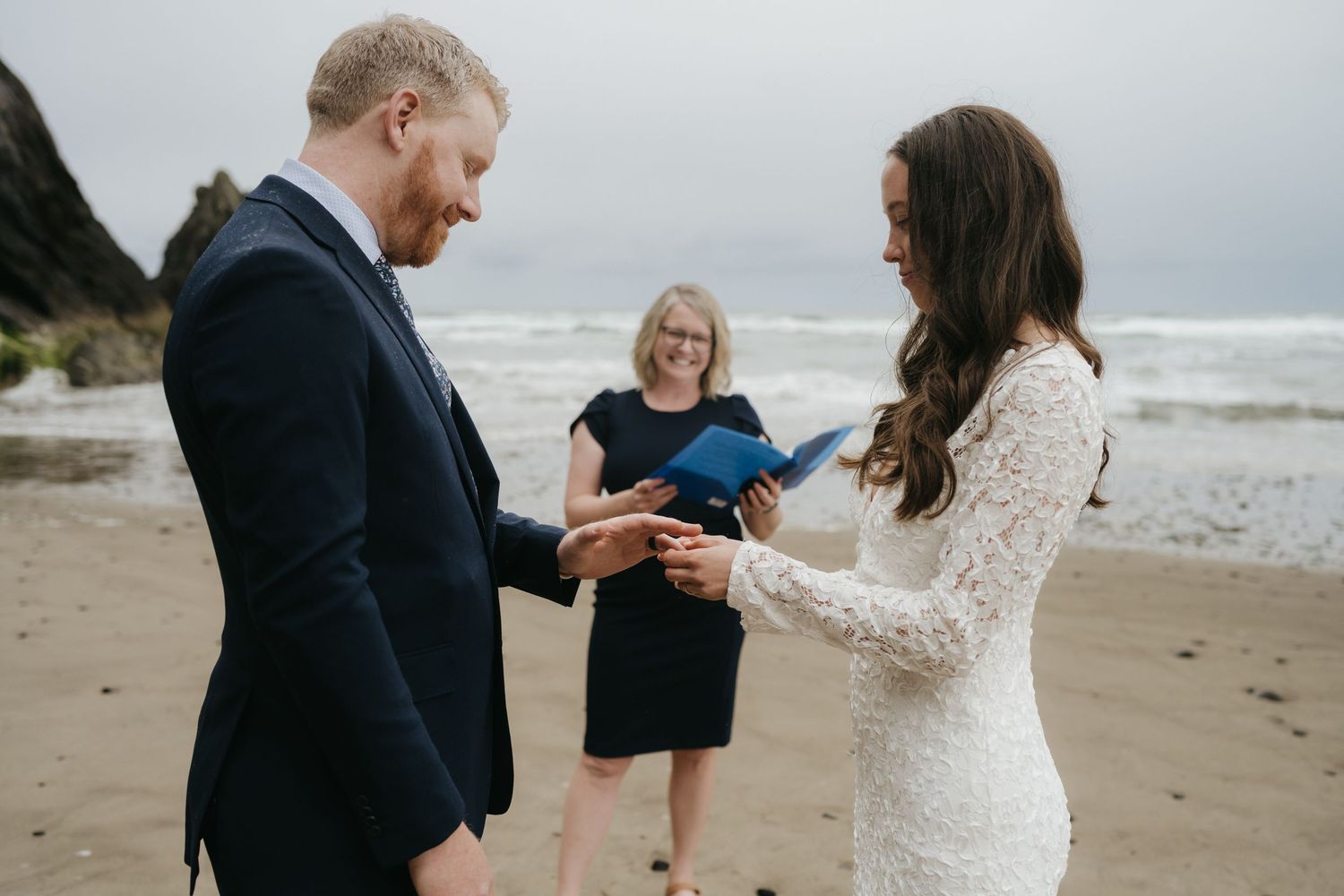 A wedding ceremony on a moody beach with cliffs in the background.