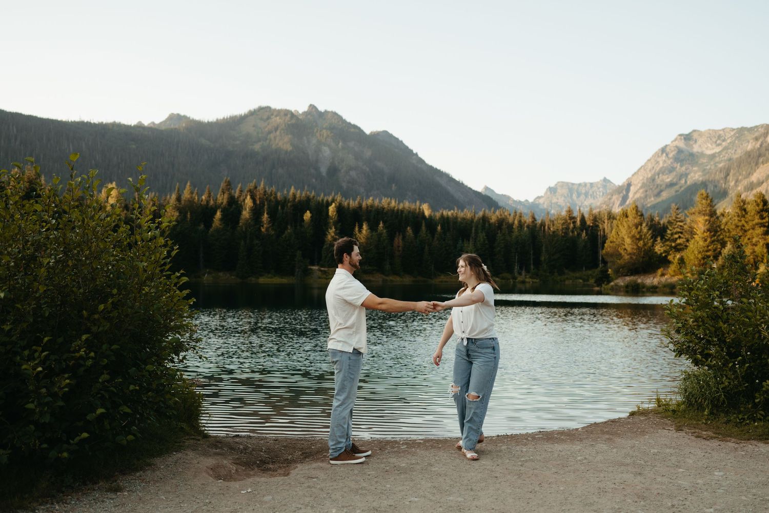 Playful dance moves against backdrop of mountain lake and autumn trees.