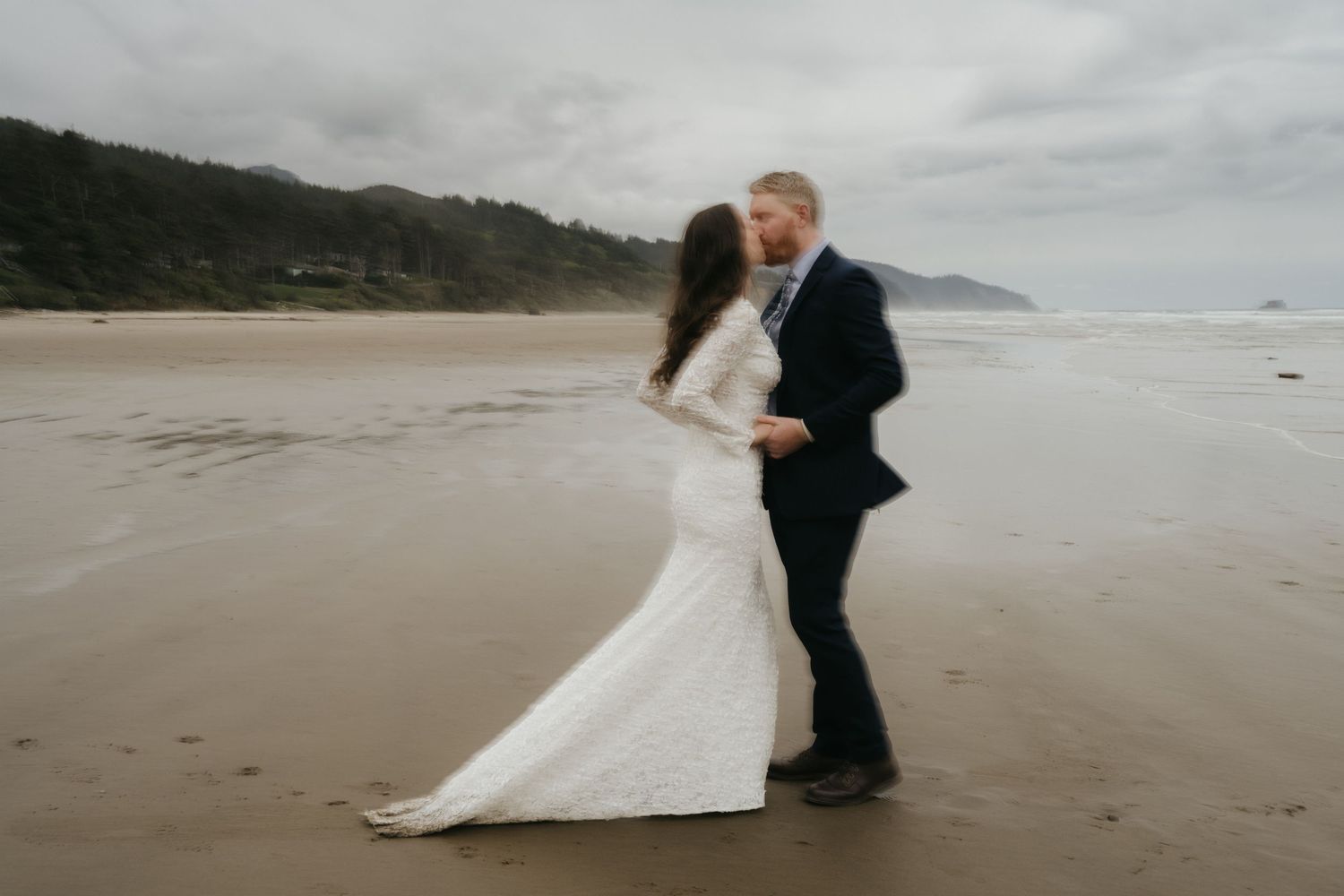 Couple dancing together on a misty beach in wedding attire.