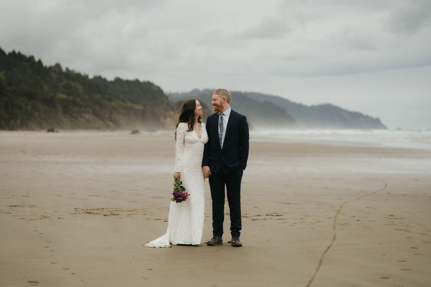 Misty coastal landscape with dramatic cliffs and sandy beach along the Pacific Northwest shore.