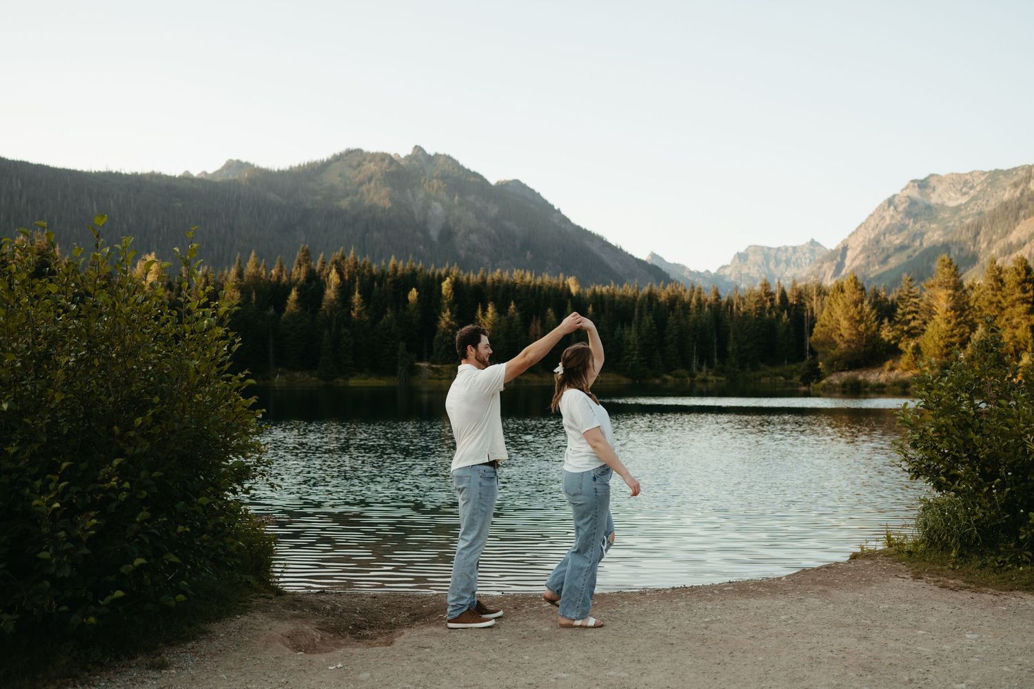 Dancing together by a scenic mountain lake during golden hour.