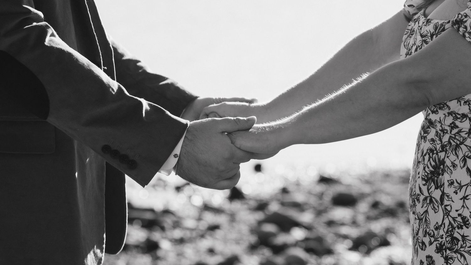 A black and white close-up of hands joining together outdoors.