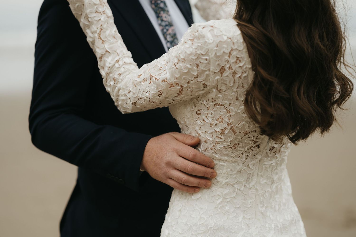 Intimate moment between newlyweds showing dress details and tender embrace.