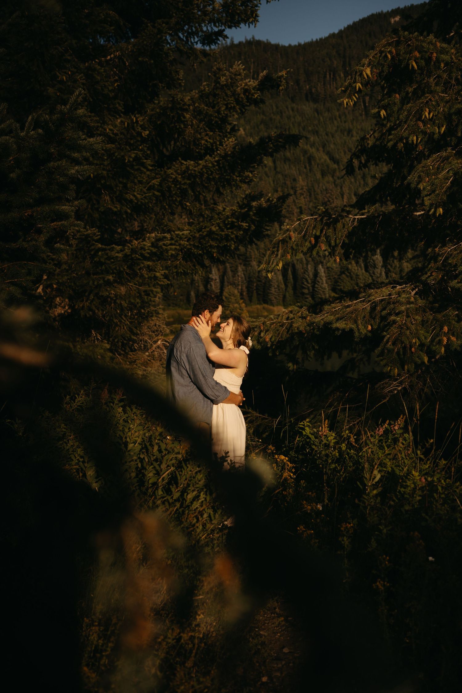Intimate couple's portrait in dramatic mountain landscape during golden hour.