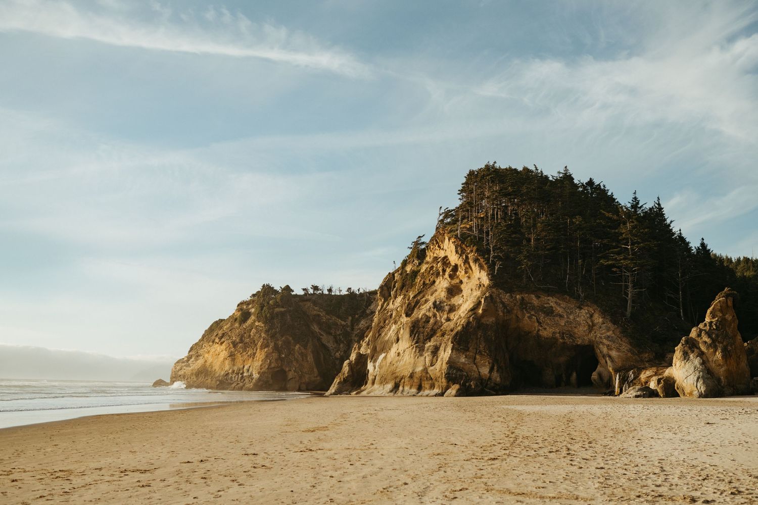 Dramatic coastal cliffs and beach landscape under blue sky.