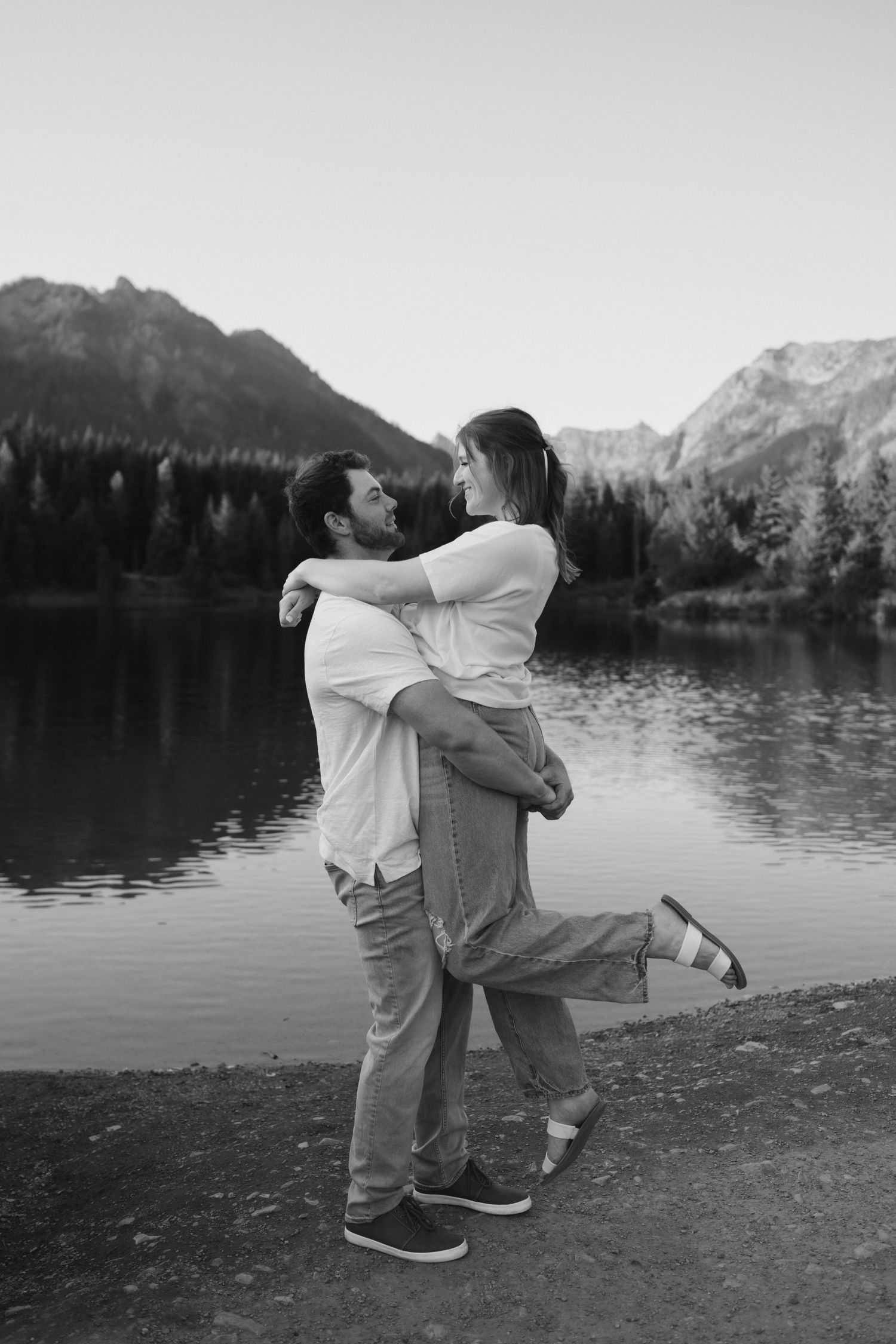 Black and white photo of embrace by scenic mountain lake.