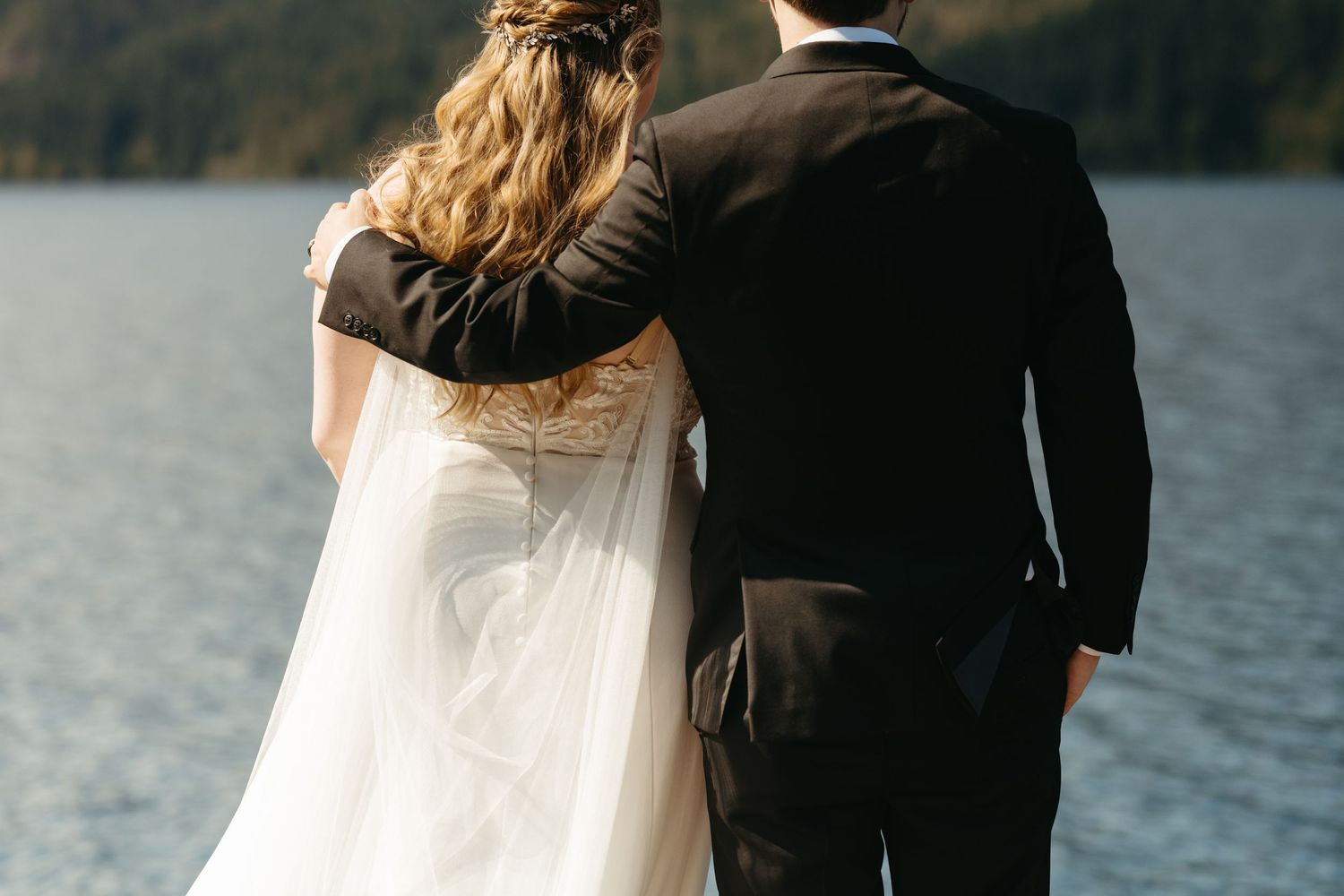 Wedding couple photographed from behind looking out over a scenic mountain lake vista.