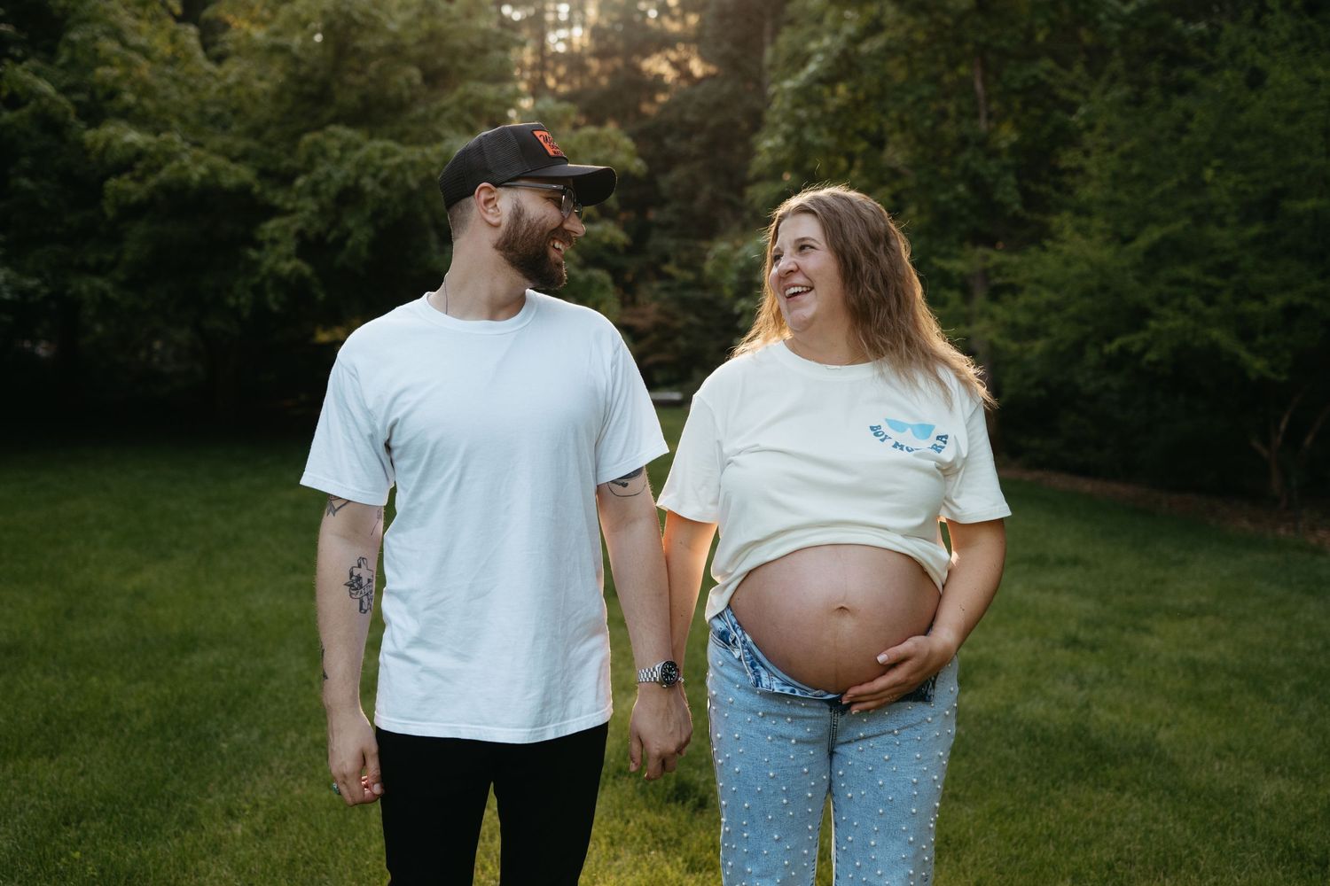 A couple poses together in a natural outdoor setting during a maternity photoshoot.