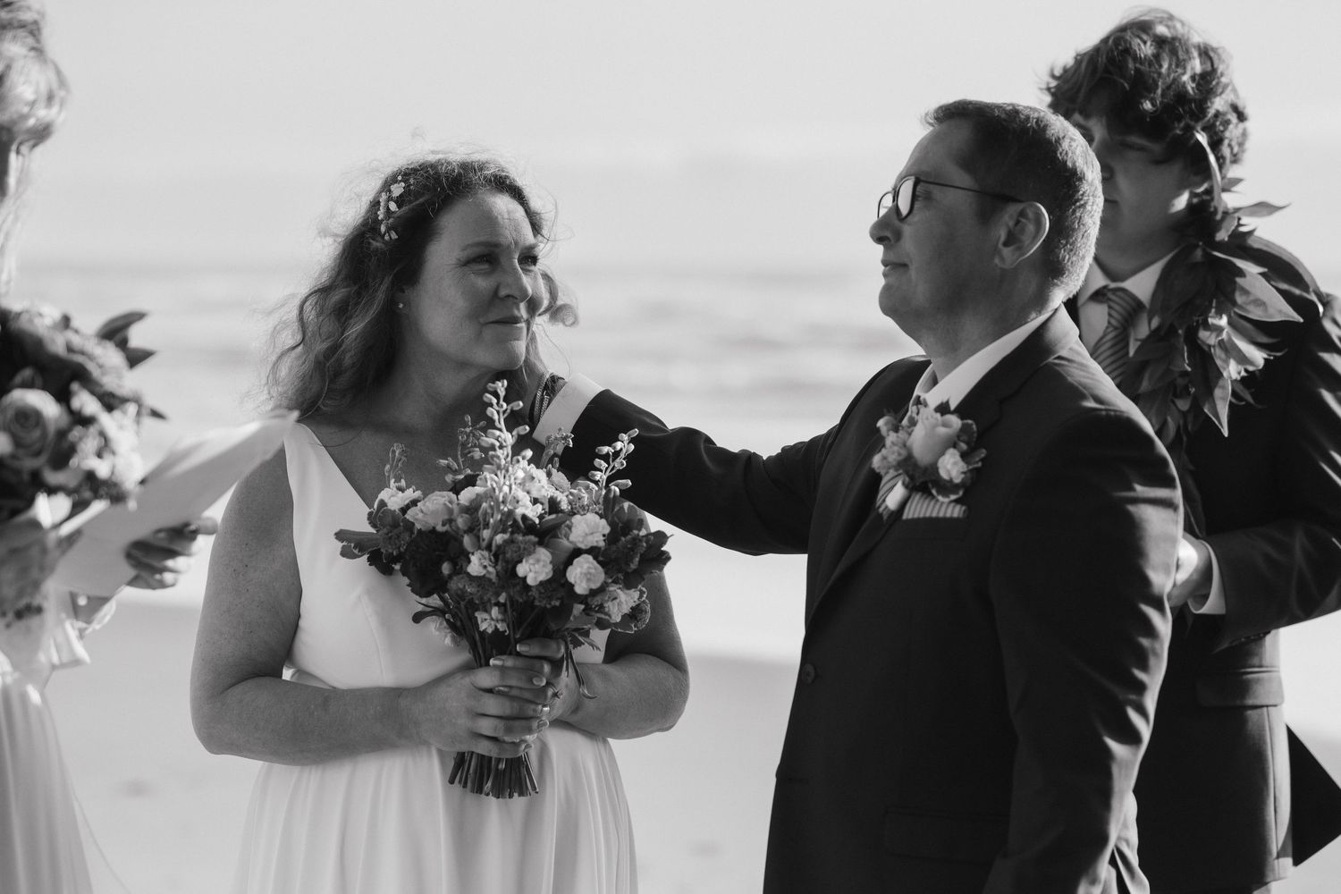 A joyful wedding celebration captured in black and white on the beach.
