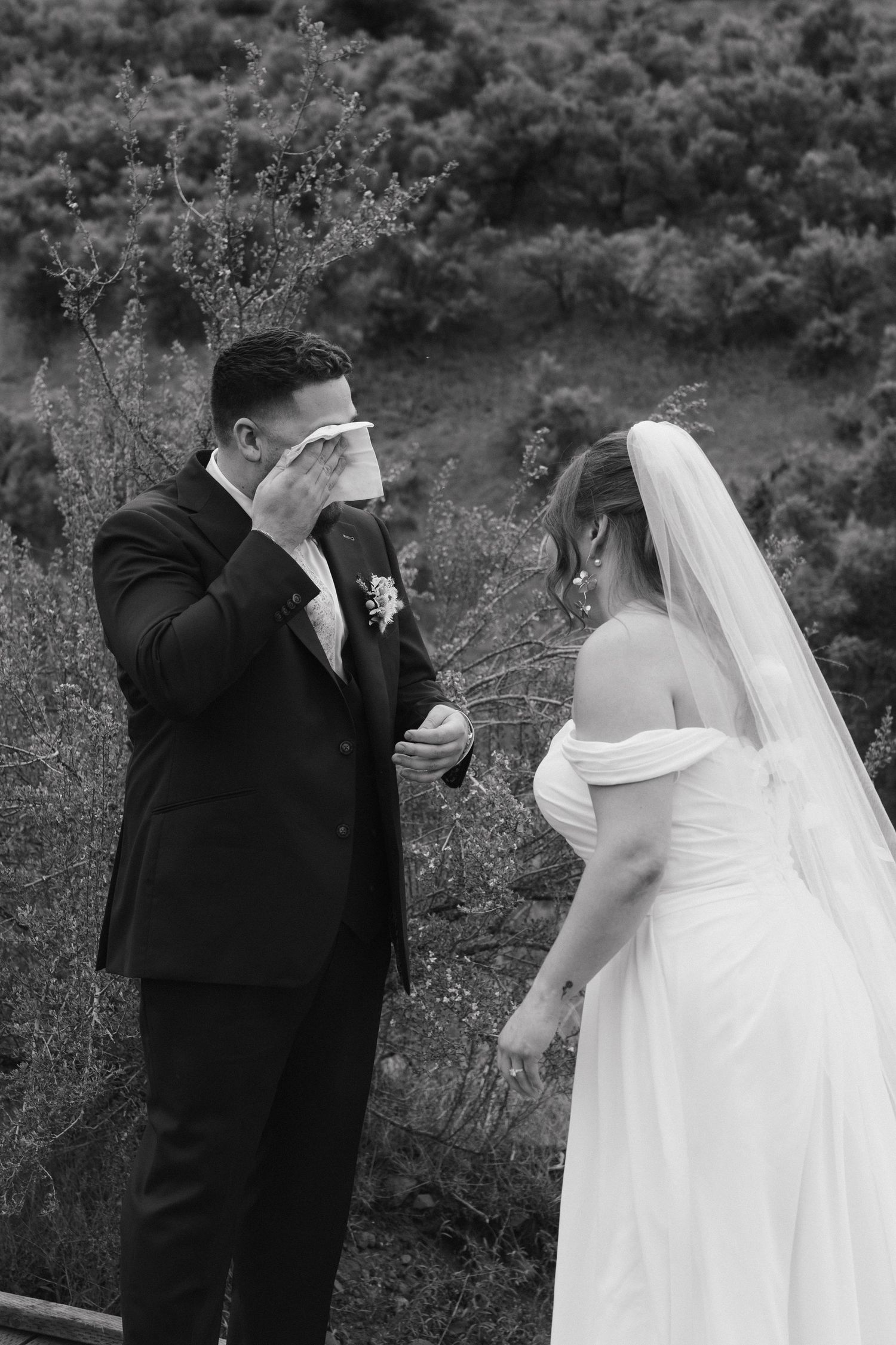 Emotional first look moment captured in black and white during outdoor wedding.