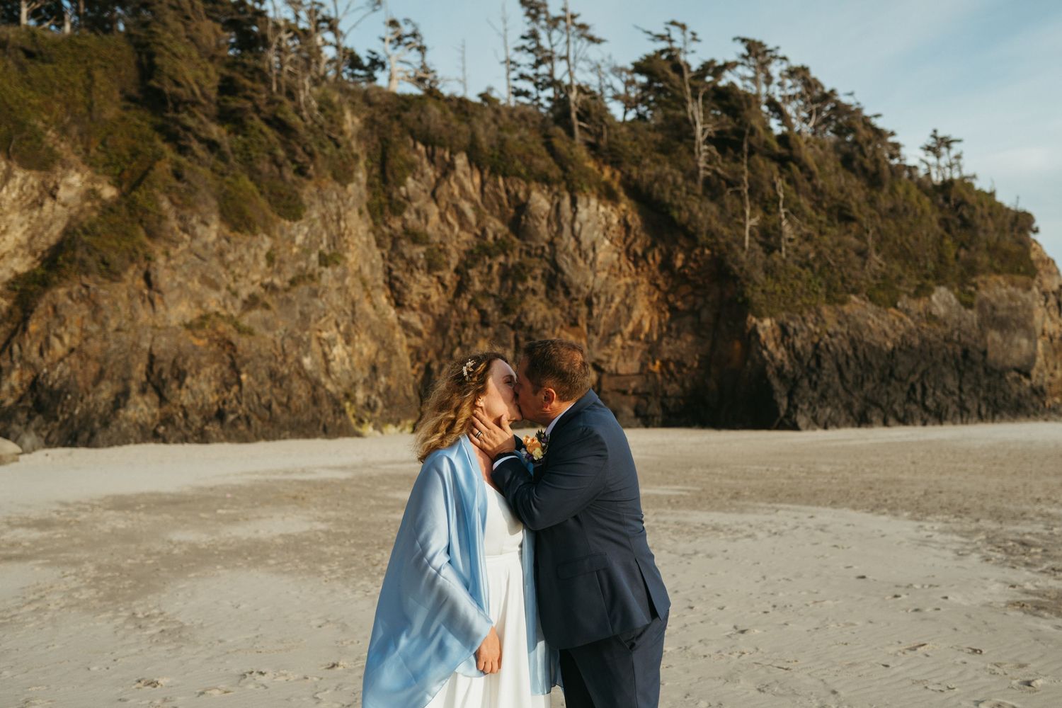 Black and white romantic beach wedding portrait with ocean waves in background.