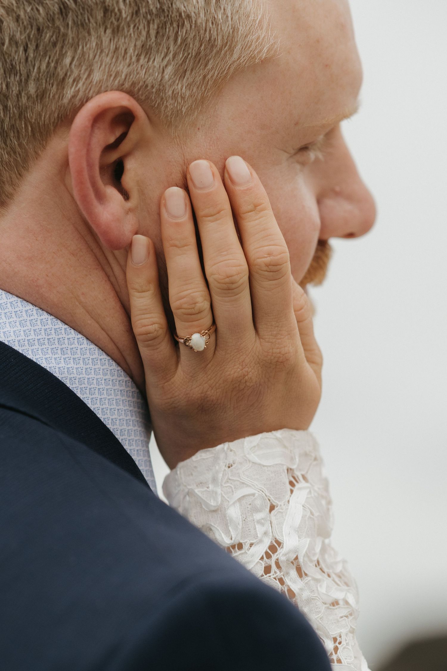 Close-up detail of an emotional moment showing hands and wedding ring.