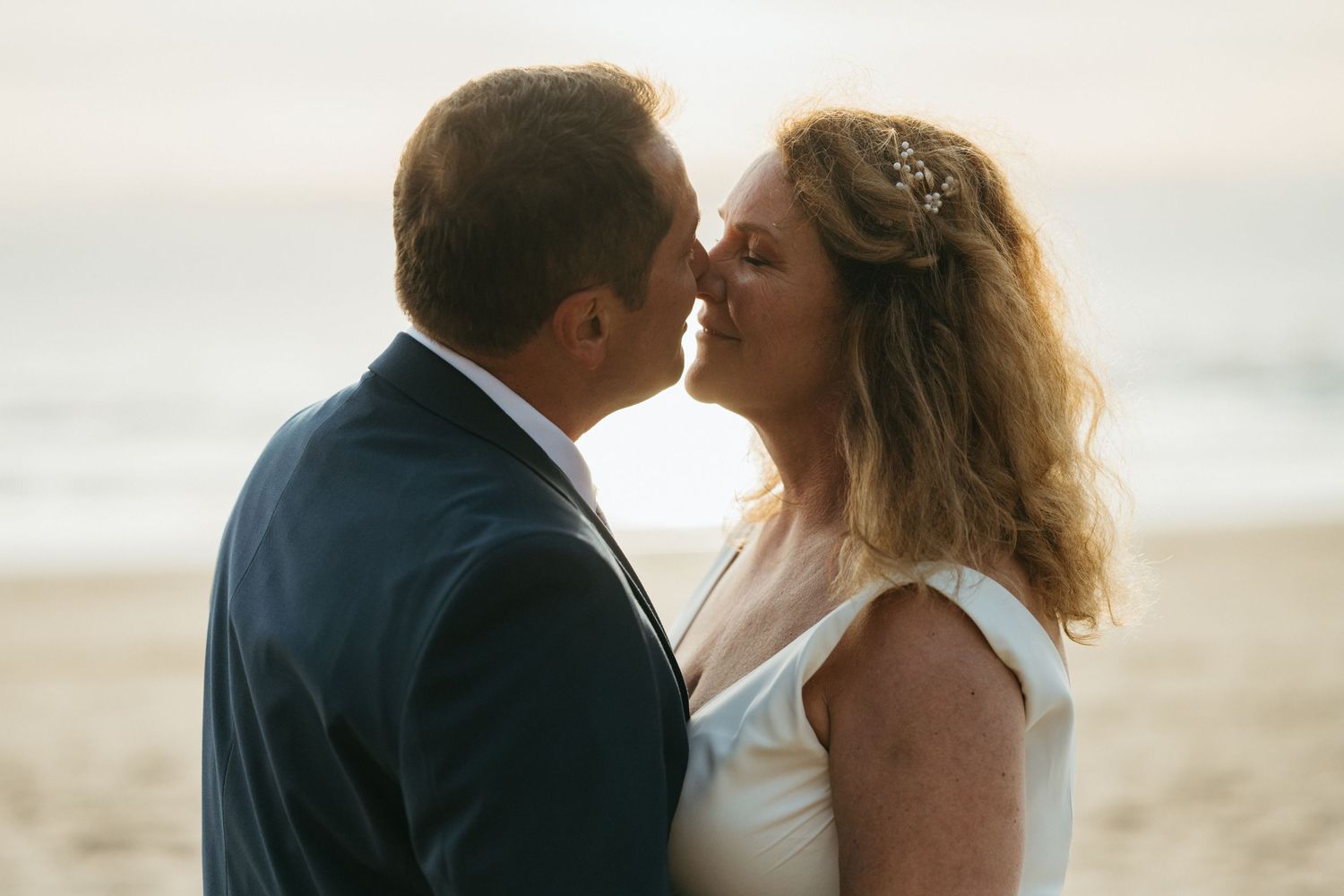 Wedding couple toasting with drinks against dramatic coastal backdrop.