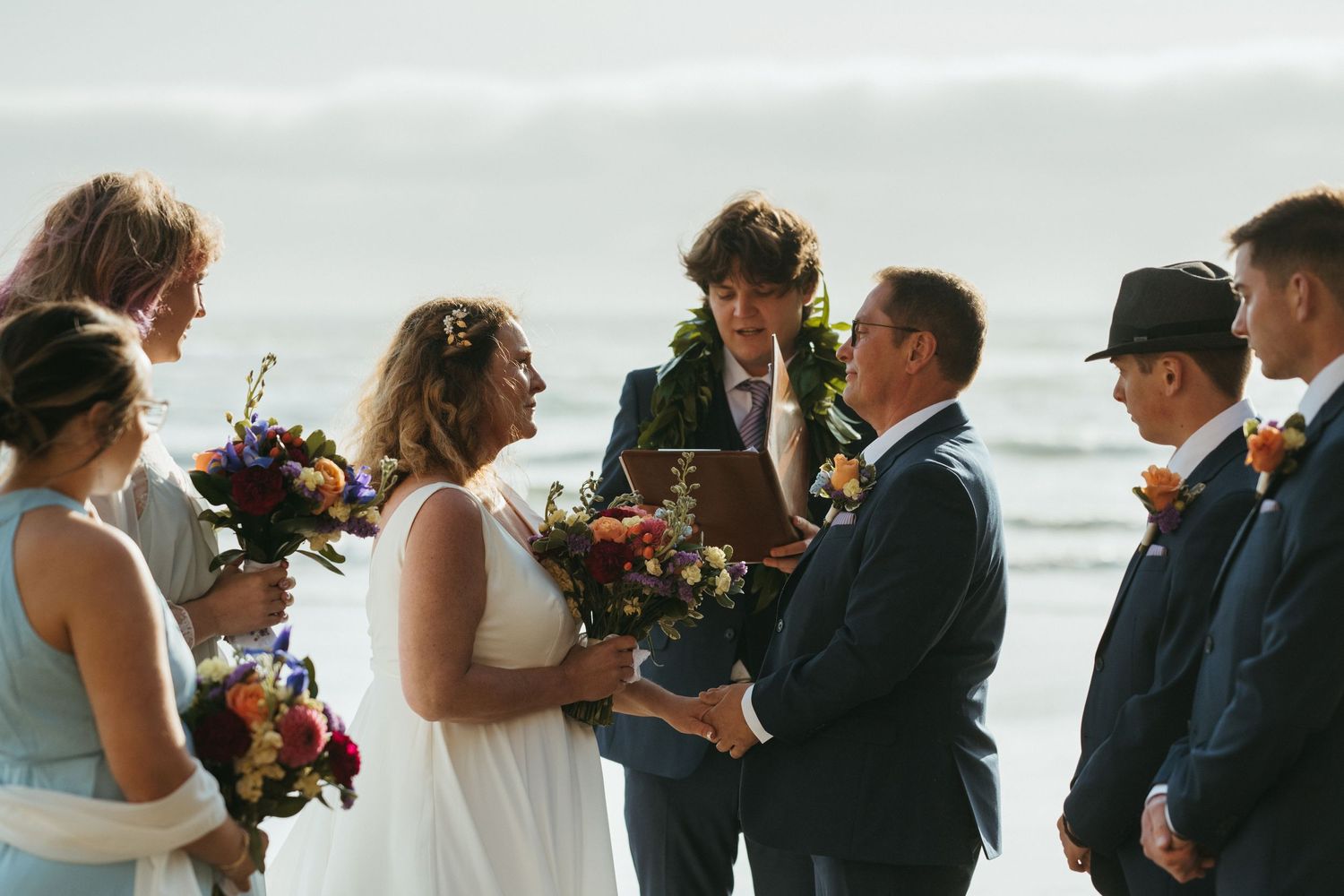 An intimate beach wedding ceremony with attendees gathered by the ocean.