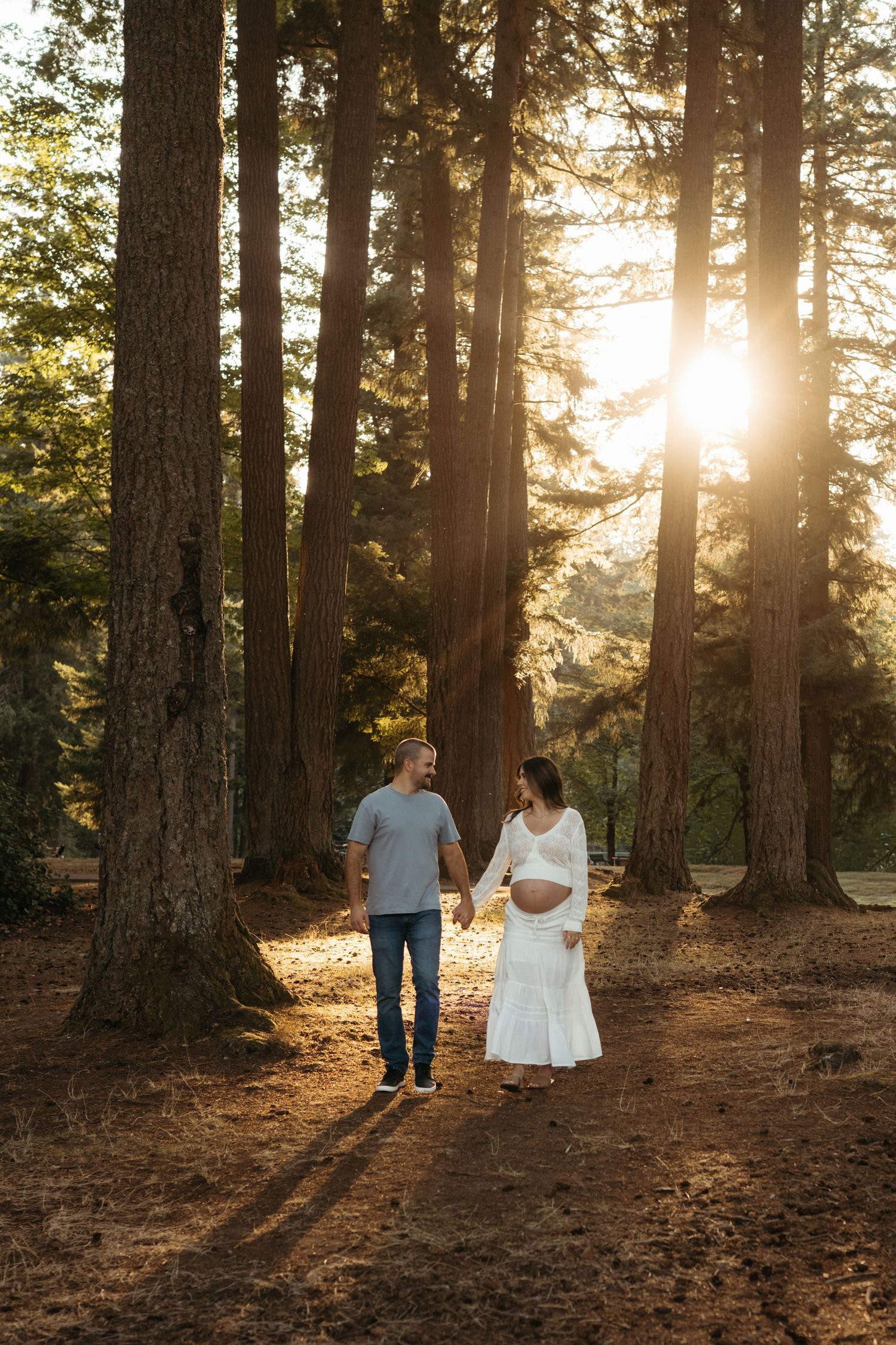 A romantic sunset photo session in a pine forest with golden light filtering through trees.