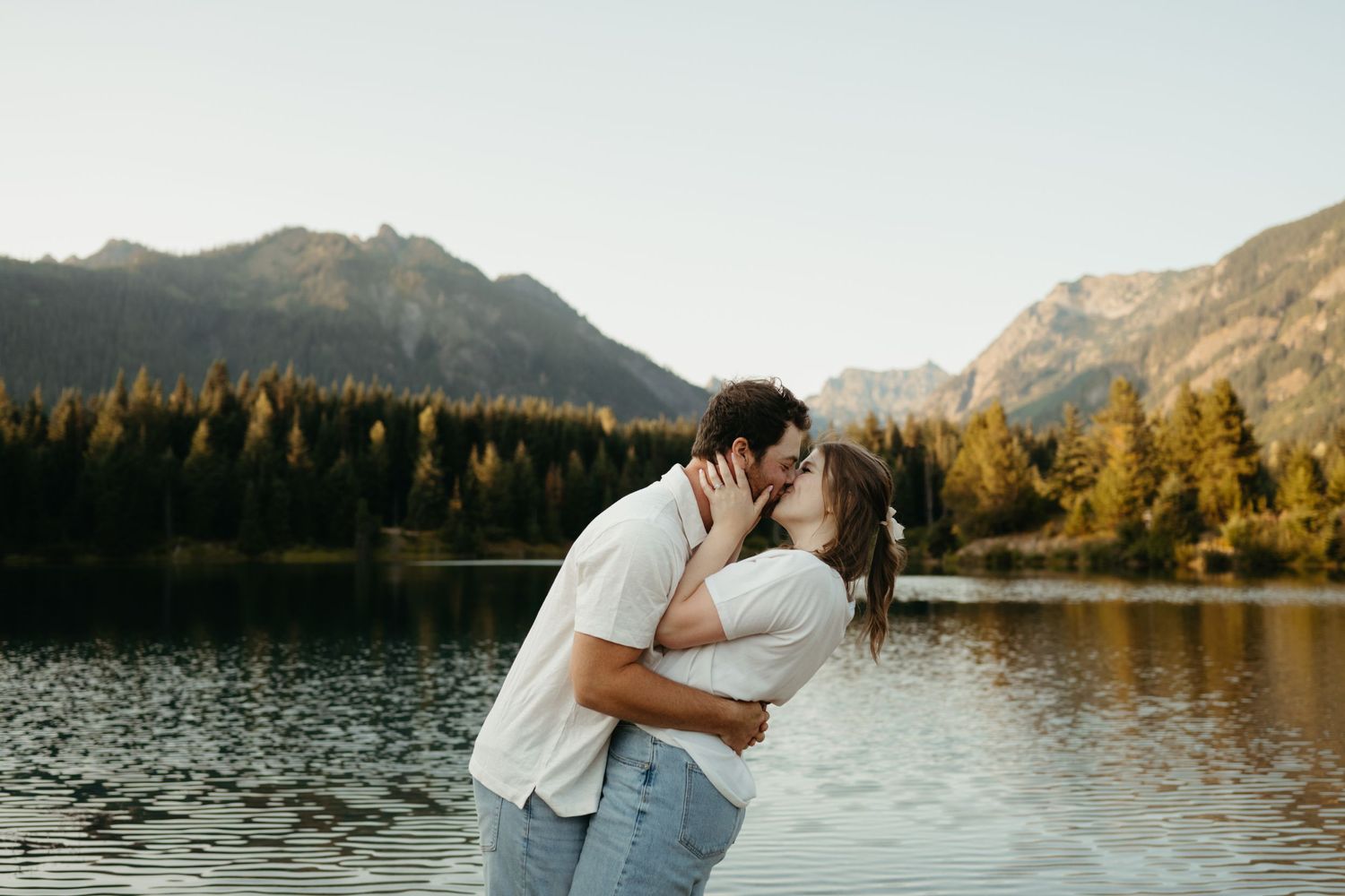 Romantic moment shared by the lake with mountains and forest creating stunning backdrop.