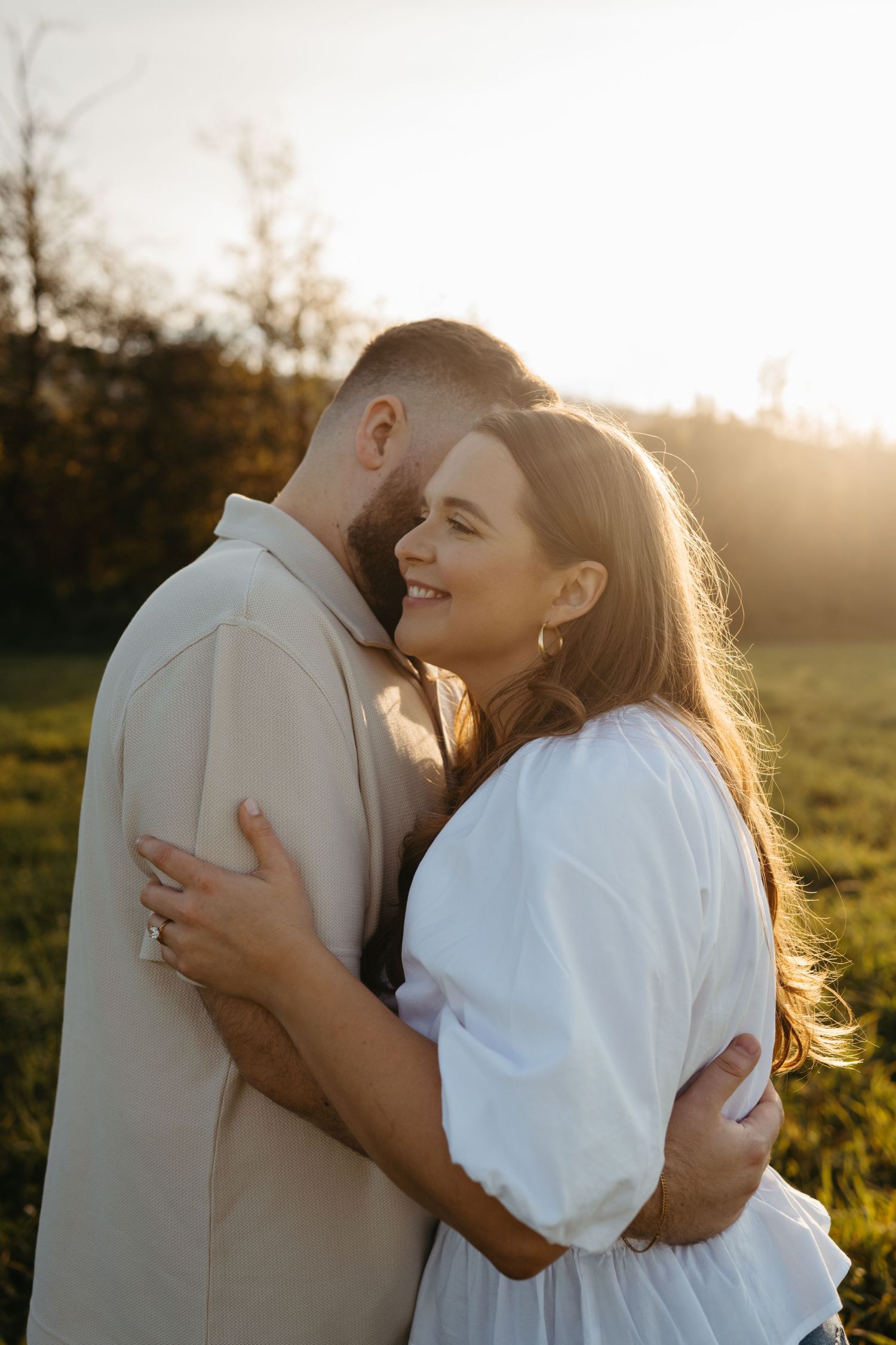 Intimate couple portrait in white outfits during golden hour with sunlit glow.