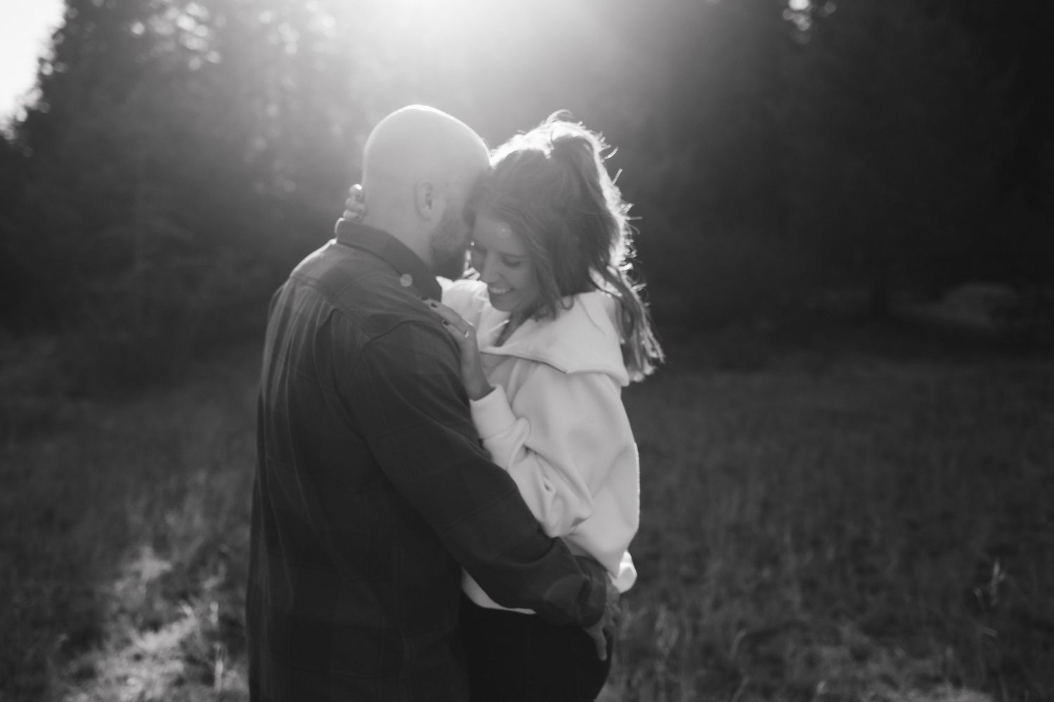 Black and white silhouettes of a couple embracing in dramatic lighting.