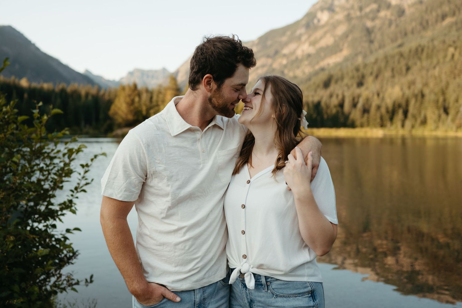Couple enjoying tender moments by a scenic mountain lake.