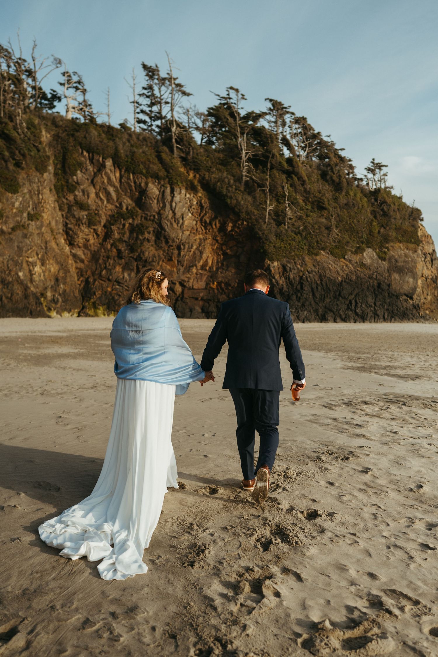 Intimate wedding moment shared on secluded beach with cliffs in background.